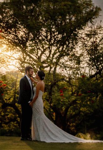 Cartagena wedding photographer capturing the couple at golden hour in a garden, warm light through trees with red flowers