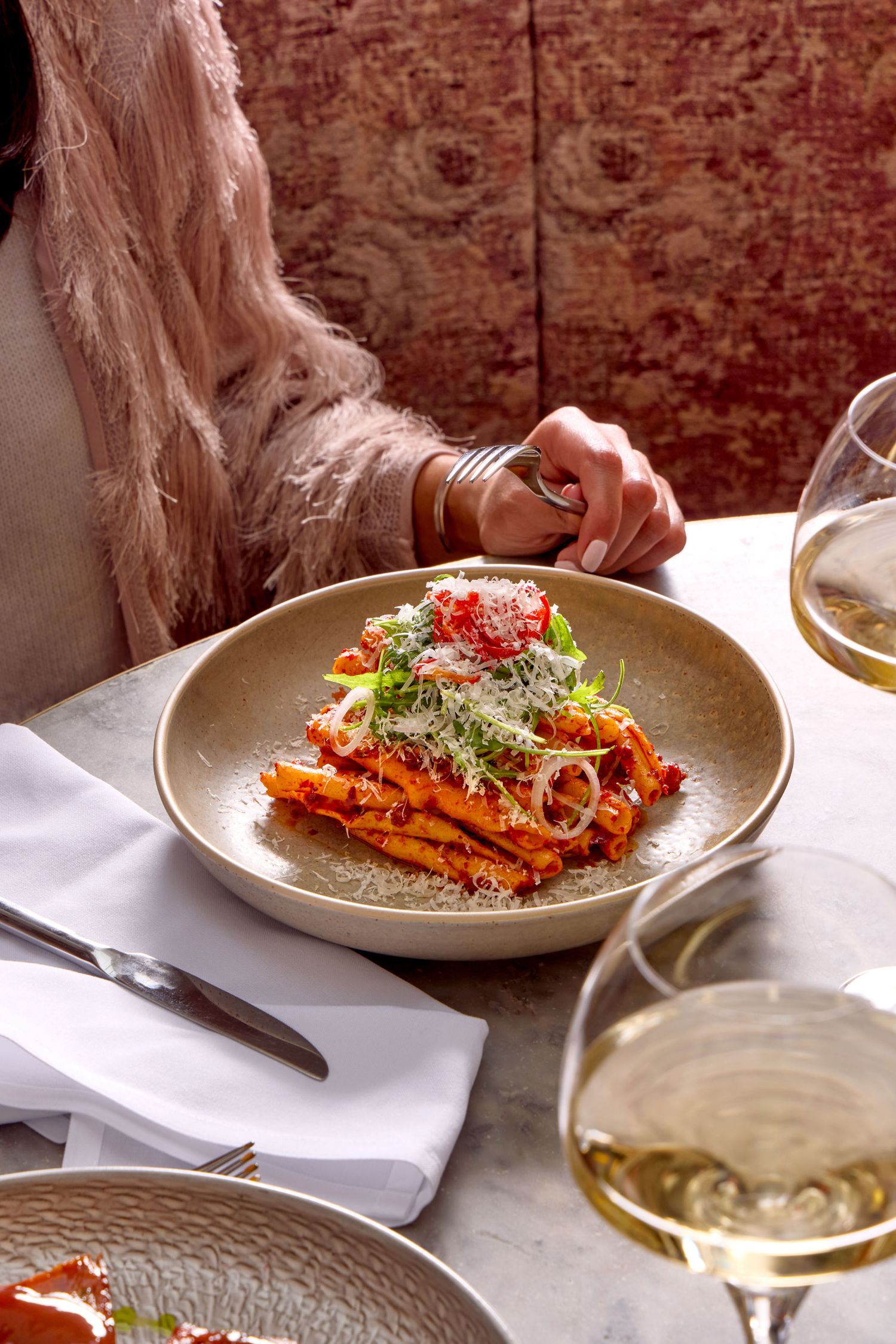 food photography captured in a restaurant in London, an elegant woman eating pasta dish