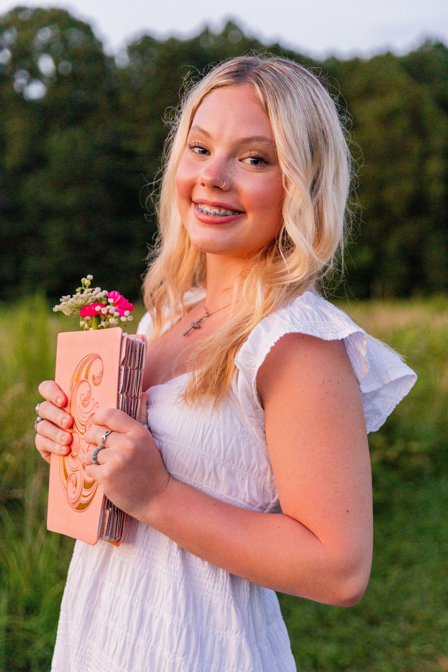 Person in white dress holding chocolate bar outdoors in sunlit field during golden hour.