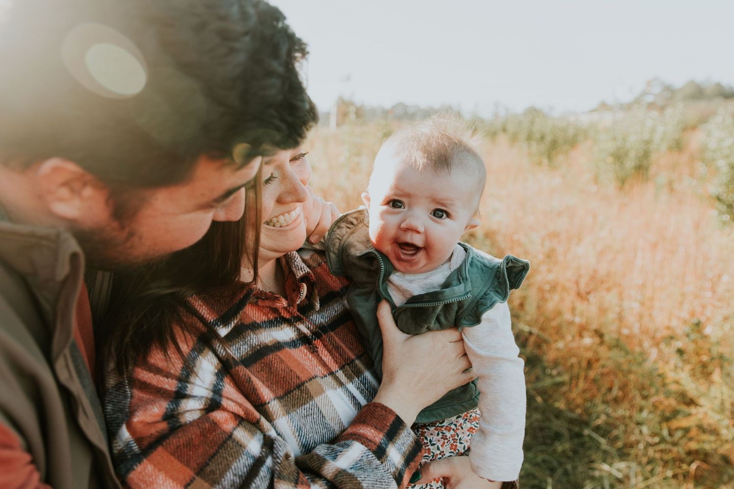 Family moment captured in golden sunlit field during autumn.