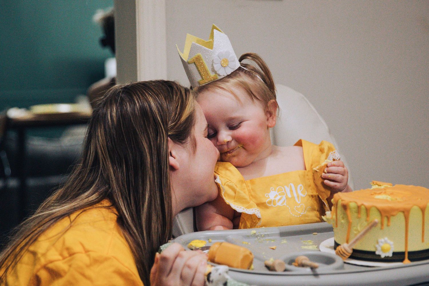 Two people in yellow shirts share a sweet moment while decorating a bright yellow cake together.