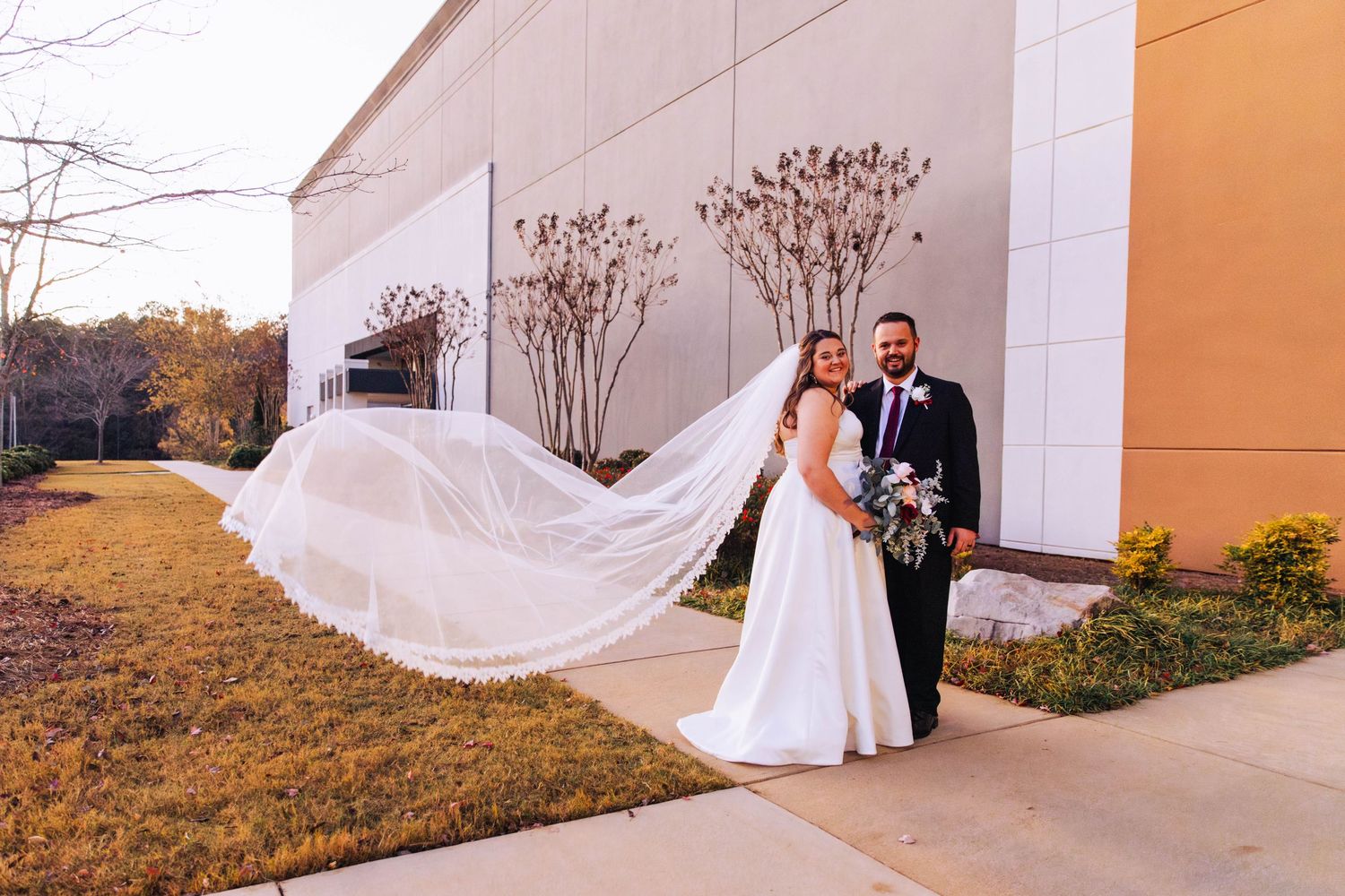 A flowing white wedding veil catches the breeze against a building exterior.