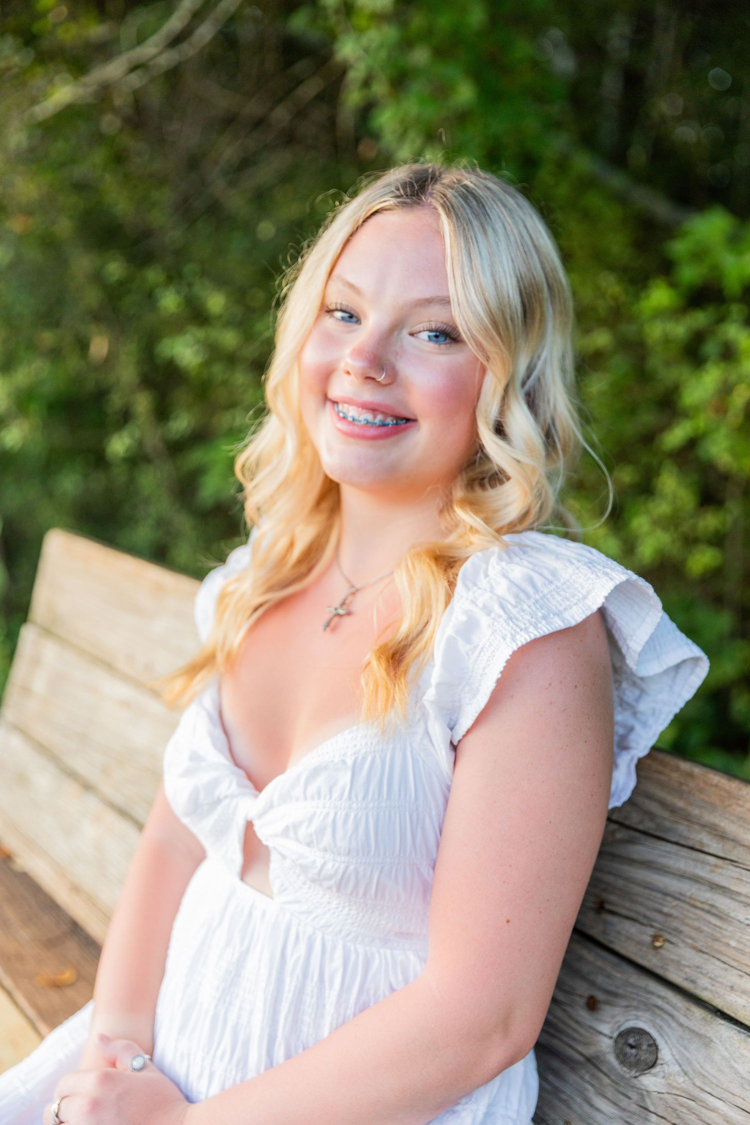 A series of outdoor portrait photos featuring someone in a white ruffled dress sitting on a wooden bench.