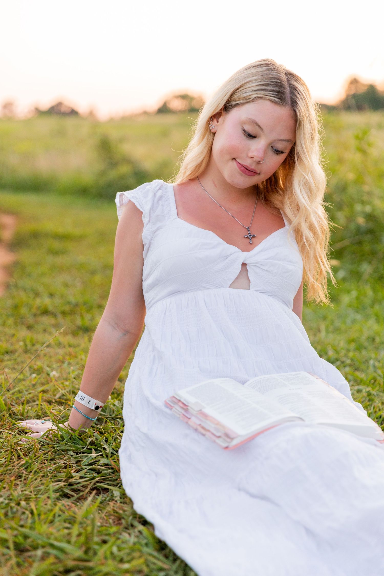 Ethereal outdoor photography featuring a flowing white dress in a sunlit meadow setting.