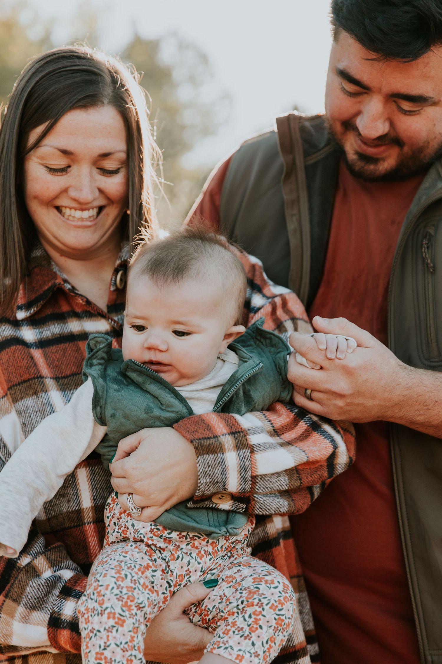 Sweet family moments captured in sequence showing parents playing with their baby wrapped in plaid.