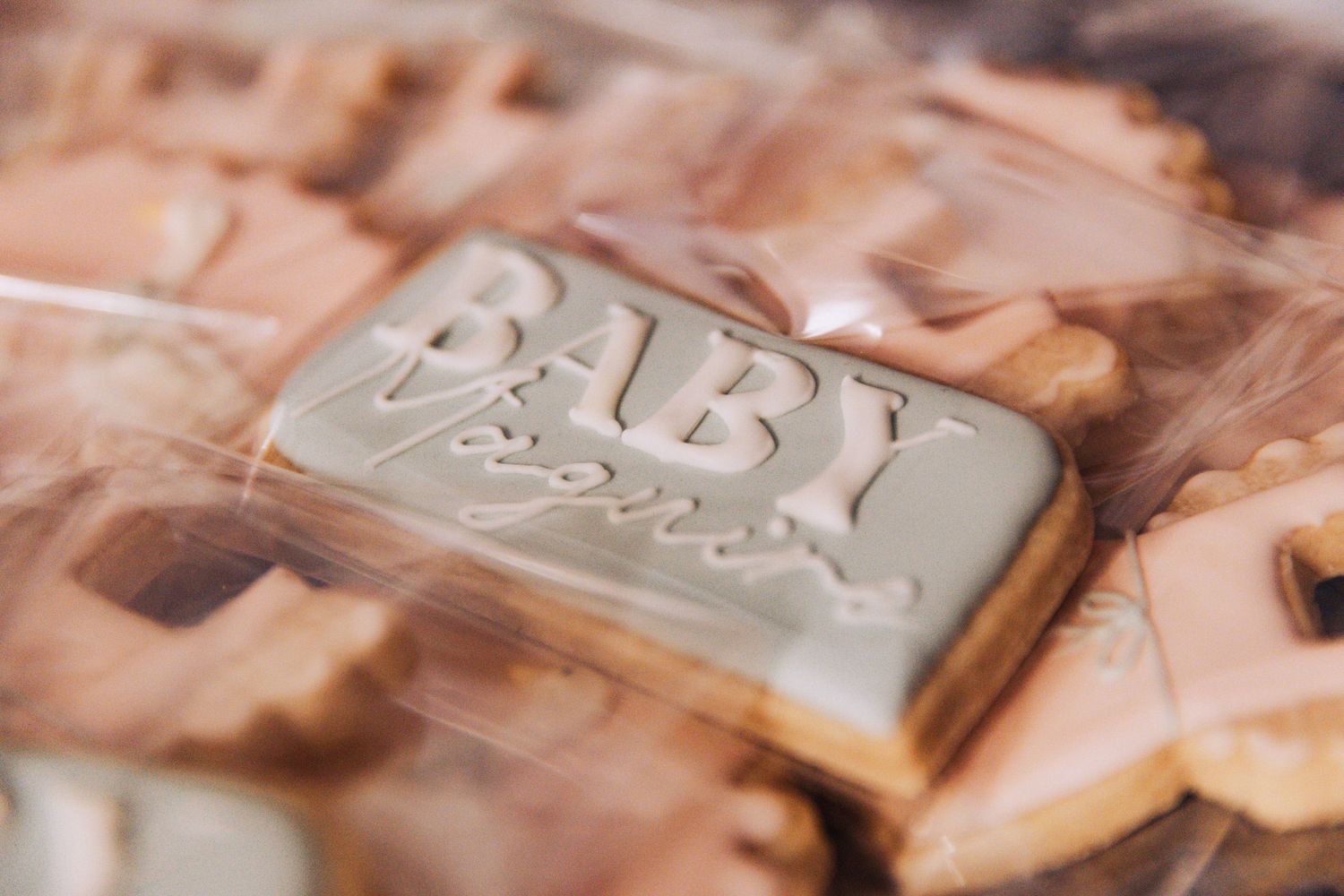 Close-up of a decorated sugar cookie with 'BABY' text in white frosting.