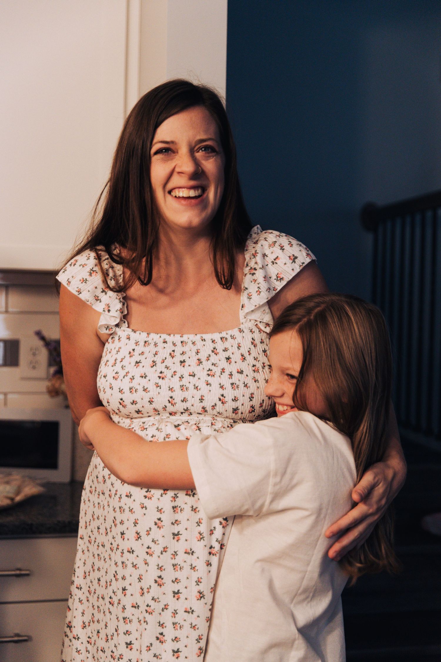 A heartwarming moment of laughter and hugs between a mother and daughter shared in a kitchen setting.