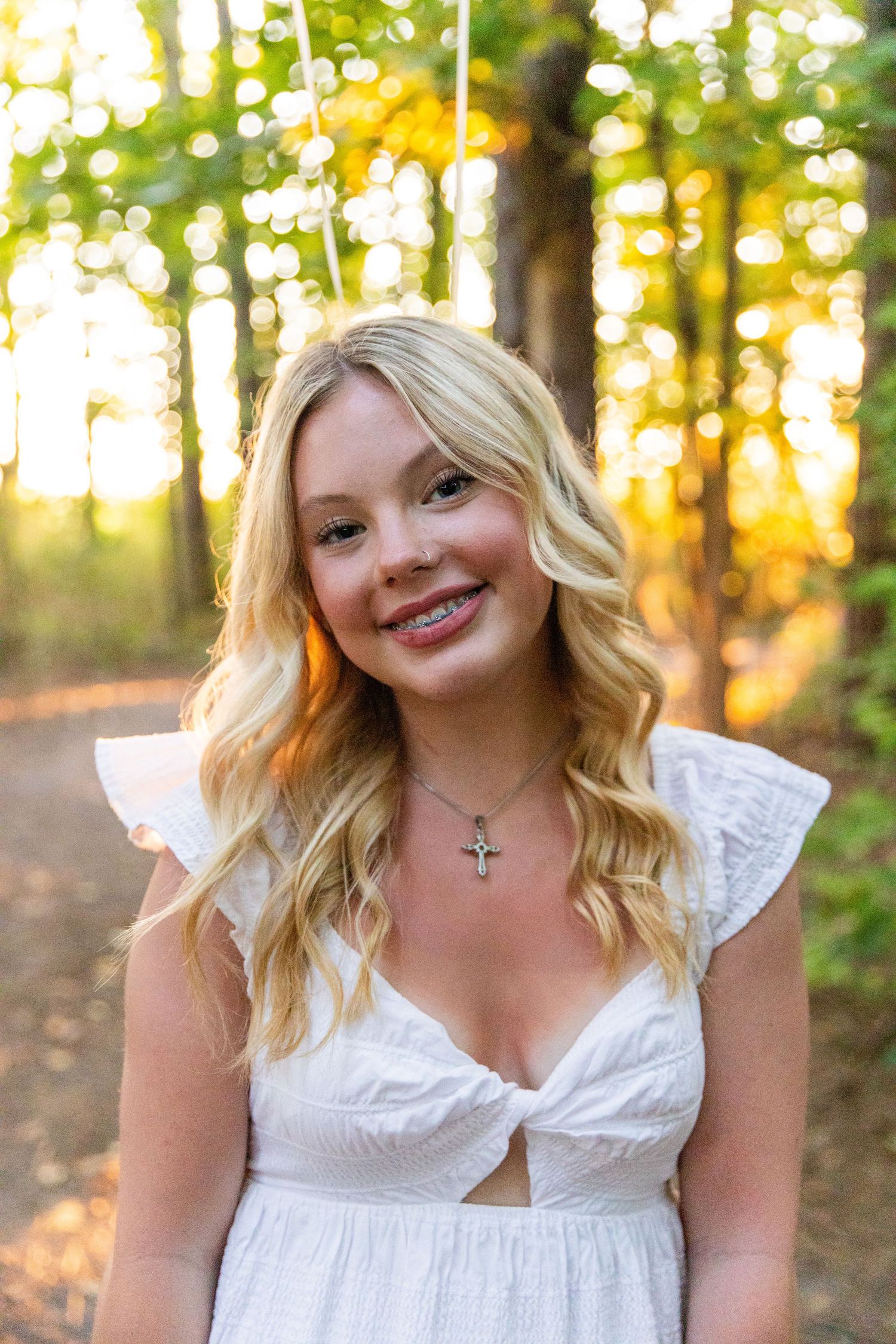 A white sundress photoshoot in a wooded area at sunset with golden light filtering through the trees.