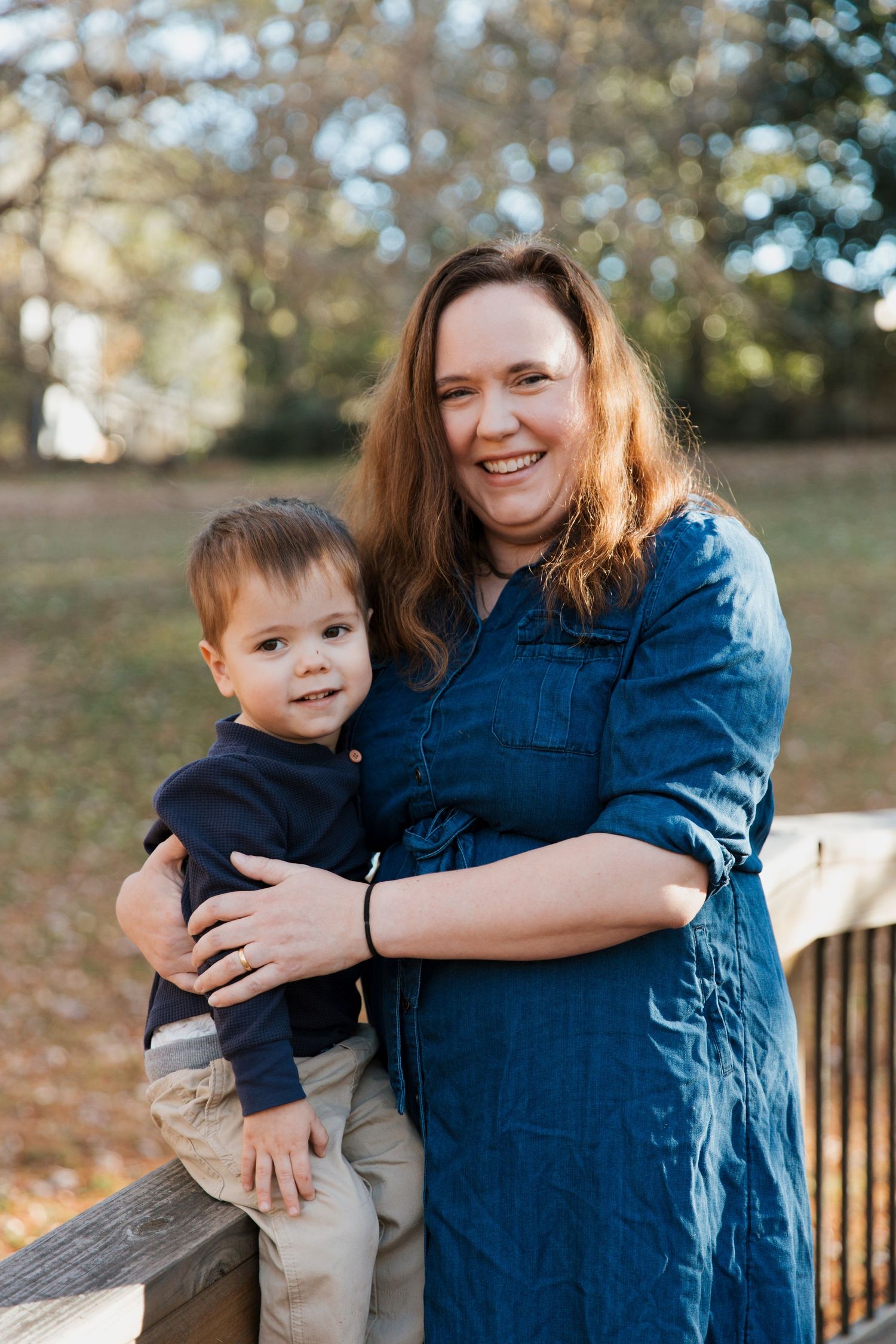 A parent and child share joyful moments together outdoors on an autumn day while wearing blue and khaki clothing.