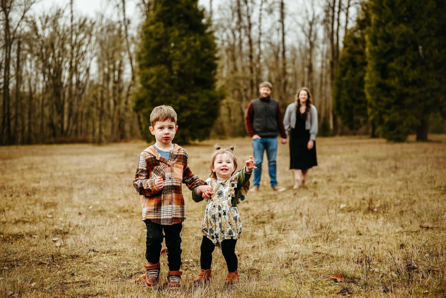 Family members walk together through a serene autumn field during a photo session at sunset.
