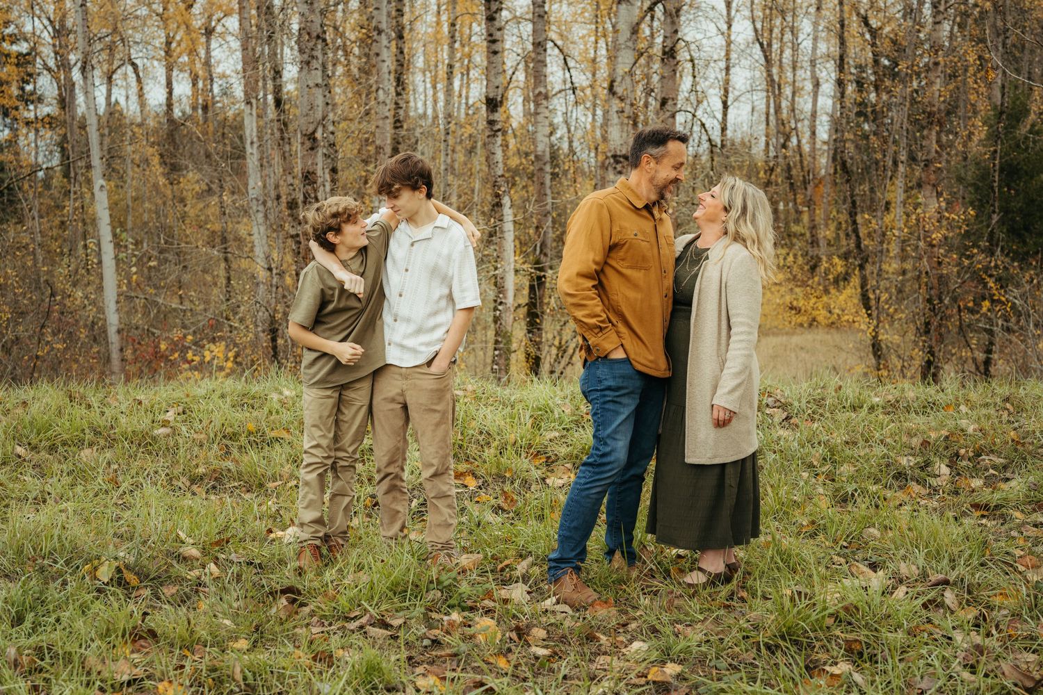Two couples enjoying conversation while standing in autumn woodland setting.