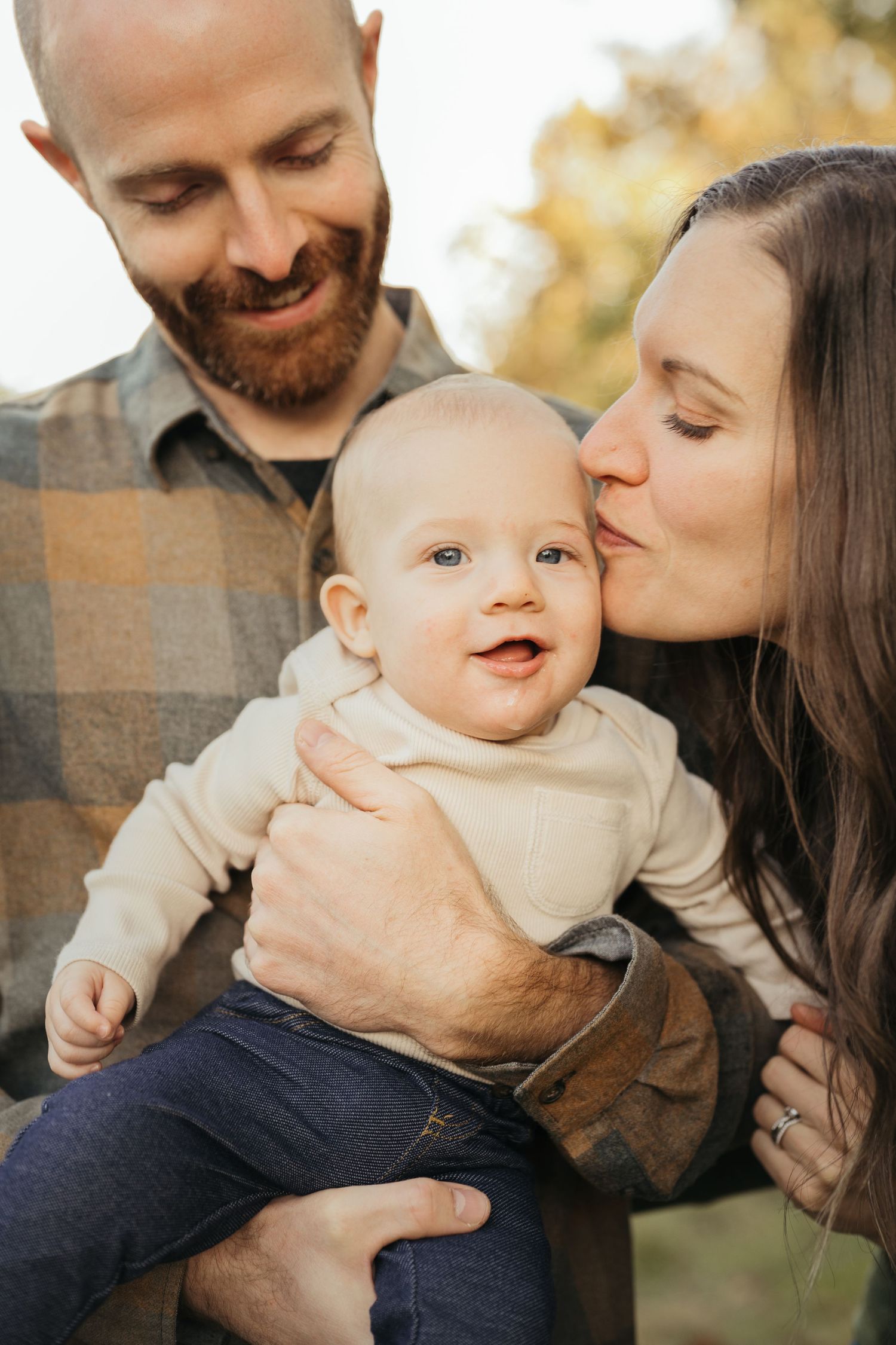 Intimate family moment captured outdoors during golden hour with warm autumn lighting.