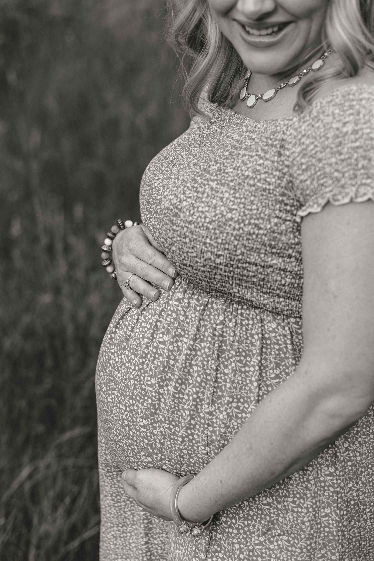 Black and white close-up of pregnancy belly in textured dress.