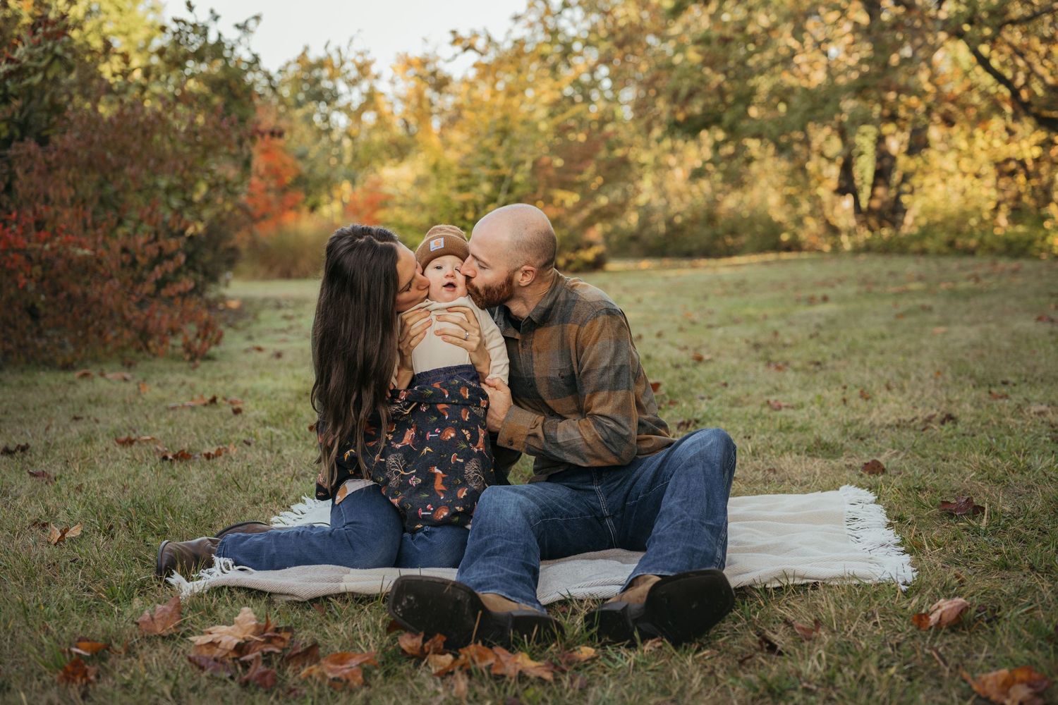 Loving family enjoying an autumn picnic together on a blanket surrounded by fall foliage.