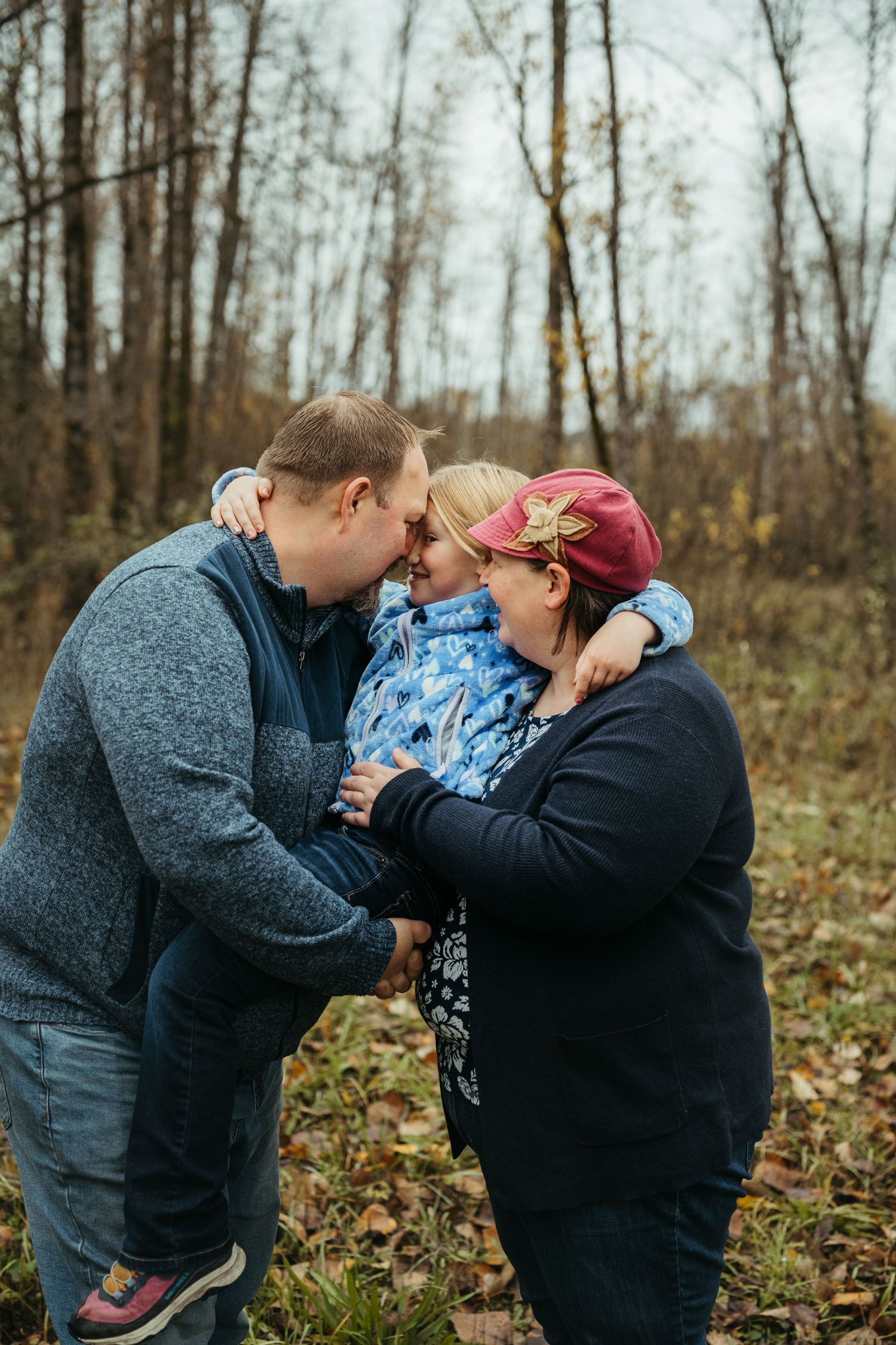 Tender family moment shared outdoors on a cool autumn day in the woods.