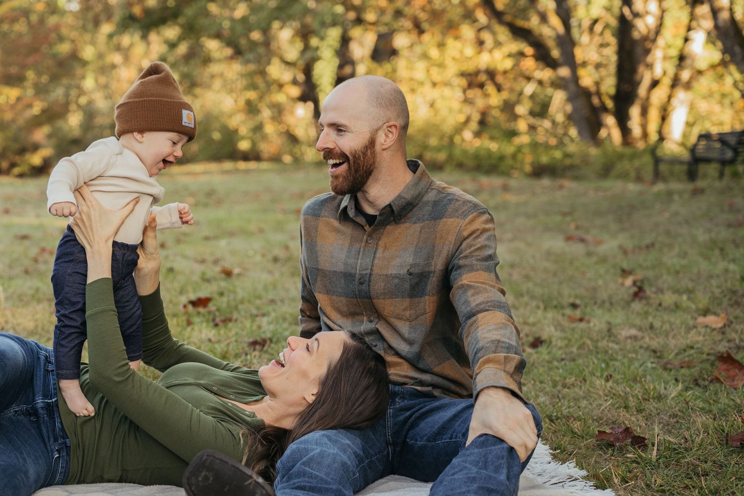 Family shares joyful moment while relaxing on blanket outdoors.