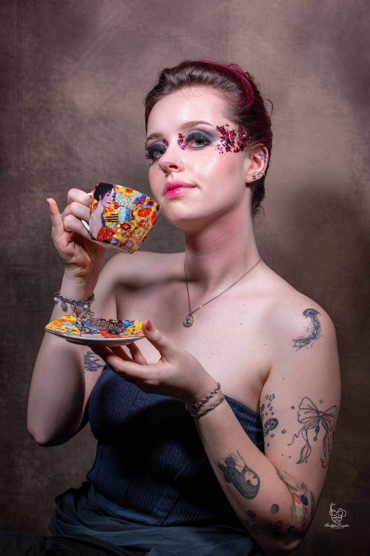 A series of artistic photos showing someone with colorful eye makeup and tattoos drinking from a teacup against a dark background.