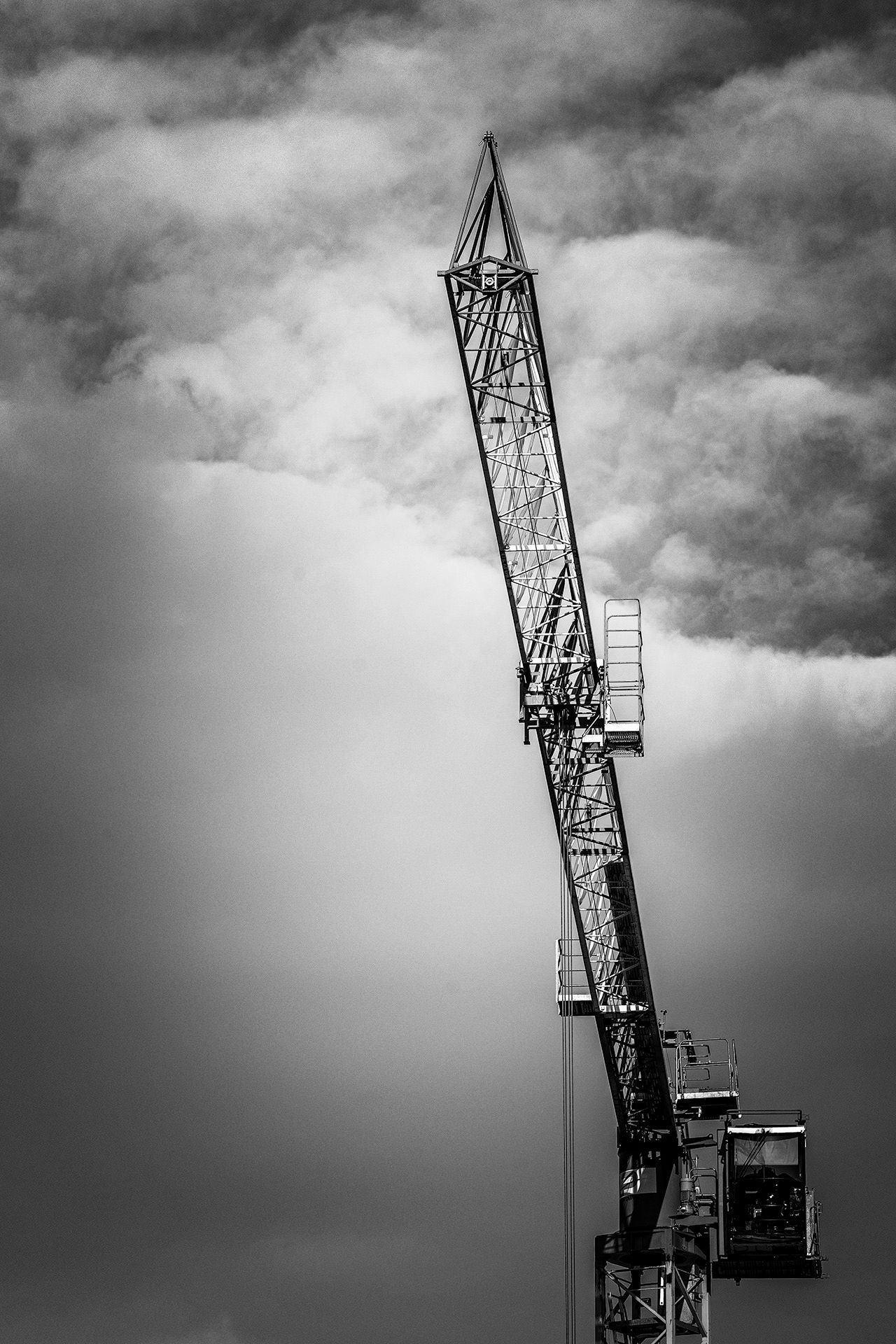 A dramatic black and white photo sequence showing a construction crane against moody storm clouds in the sky.