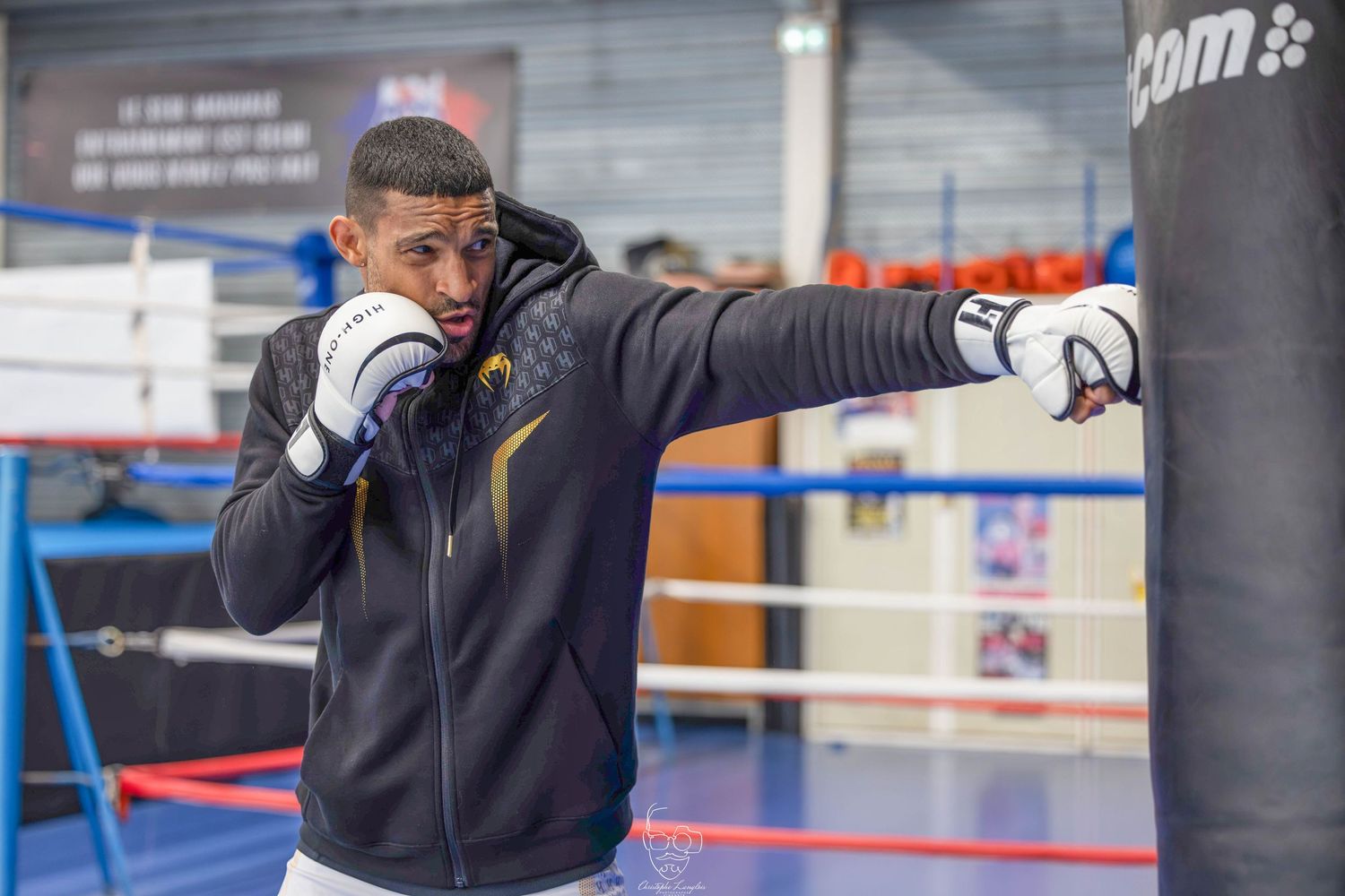 Boxer practicing punches with a heavy bag in a professional training facility.