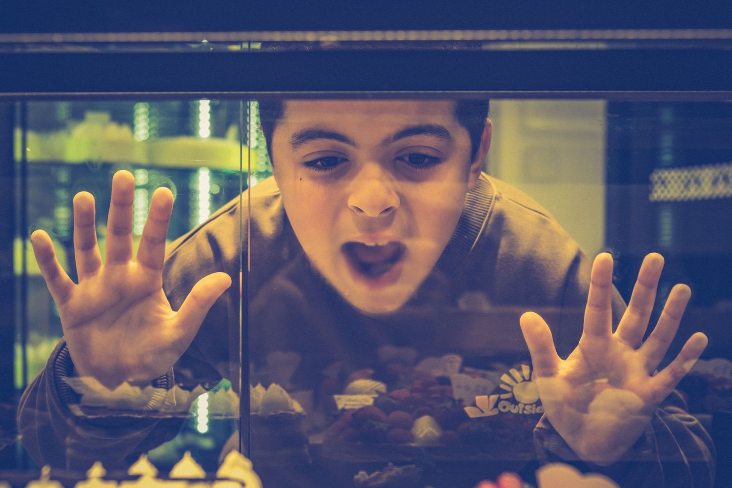 Someone makes a silly face and presses hands against glass window with dramatic expression.