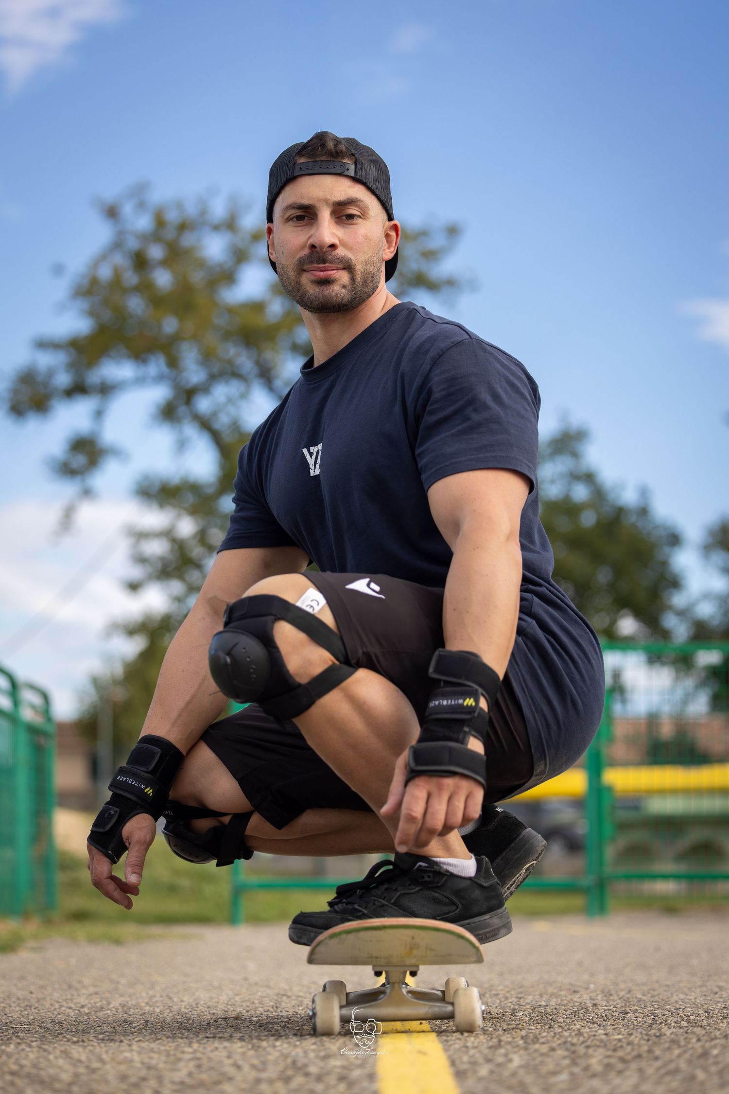 A person performs a low crouching trick on a skateboard, demonstrating balance and control on a paved surface.