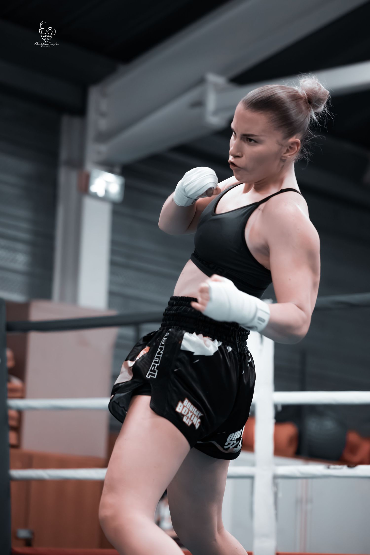 Boxer in training wearing black shorts and protective gear in a boxing ring.