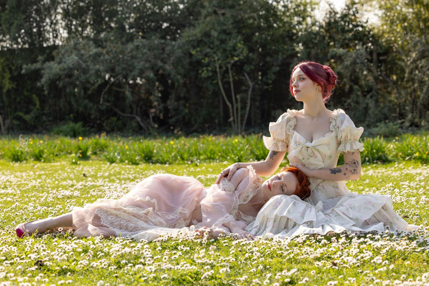 Someone in a vintage dress lies in a meadow of white daisies during golden hour, creating a dreamy spring scene.