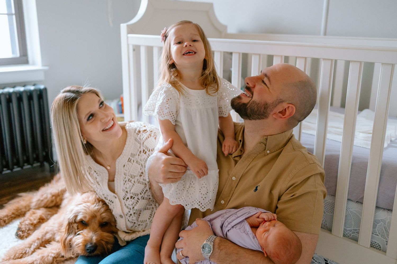 Grand Rapids newborn photographer captures joyful in-home newborn session with cozy family photography poses and sweet sibling moments.