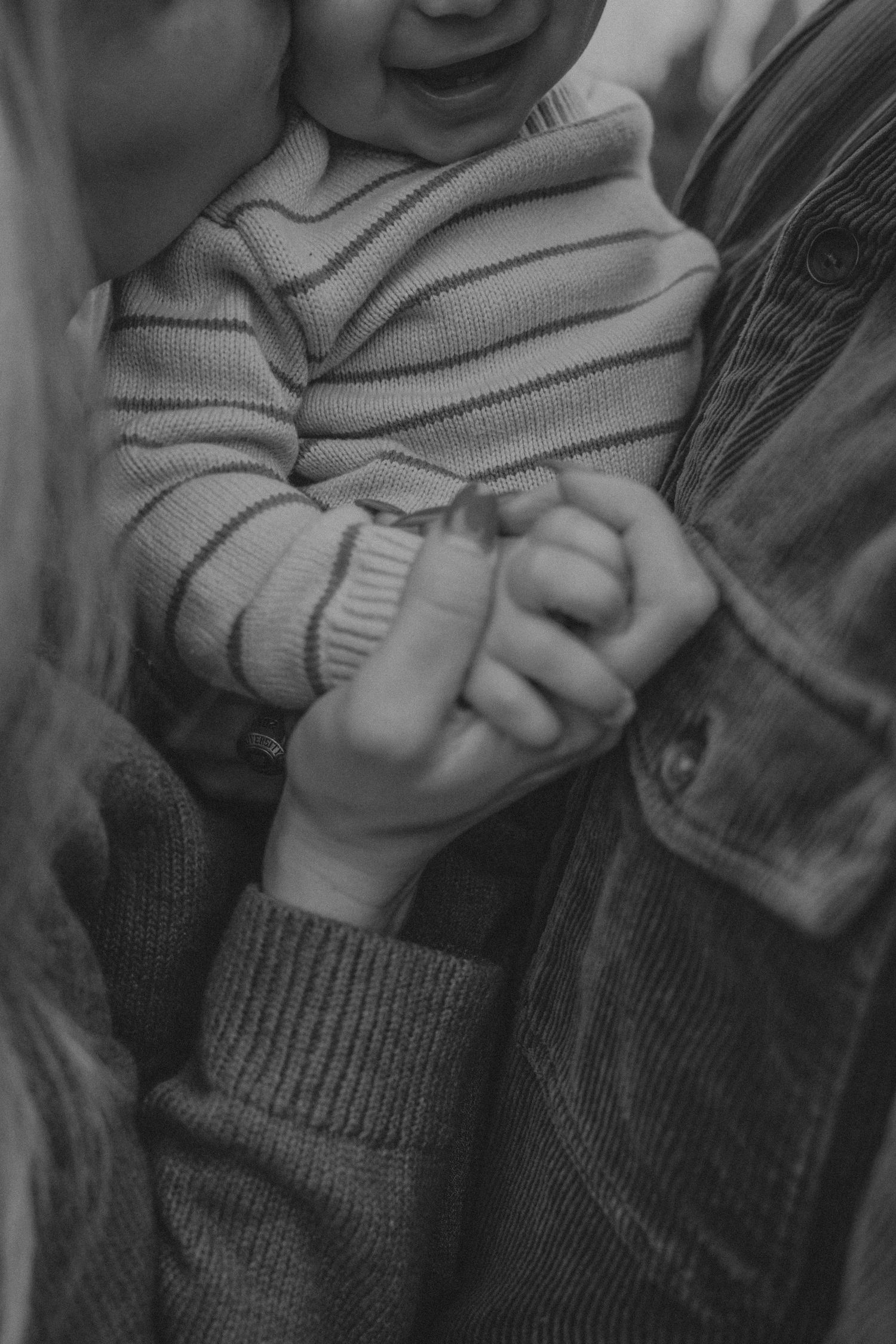 A sequence of black and white photos showing small hands grasping and playing with a knit sweater.