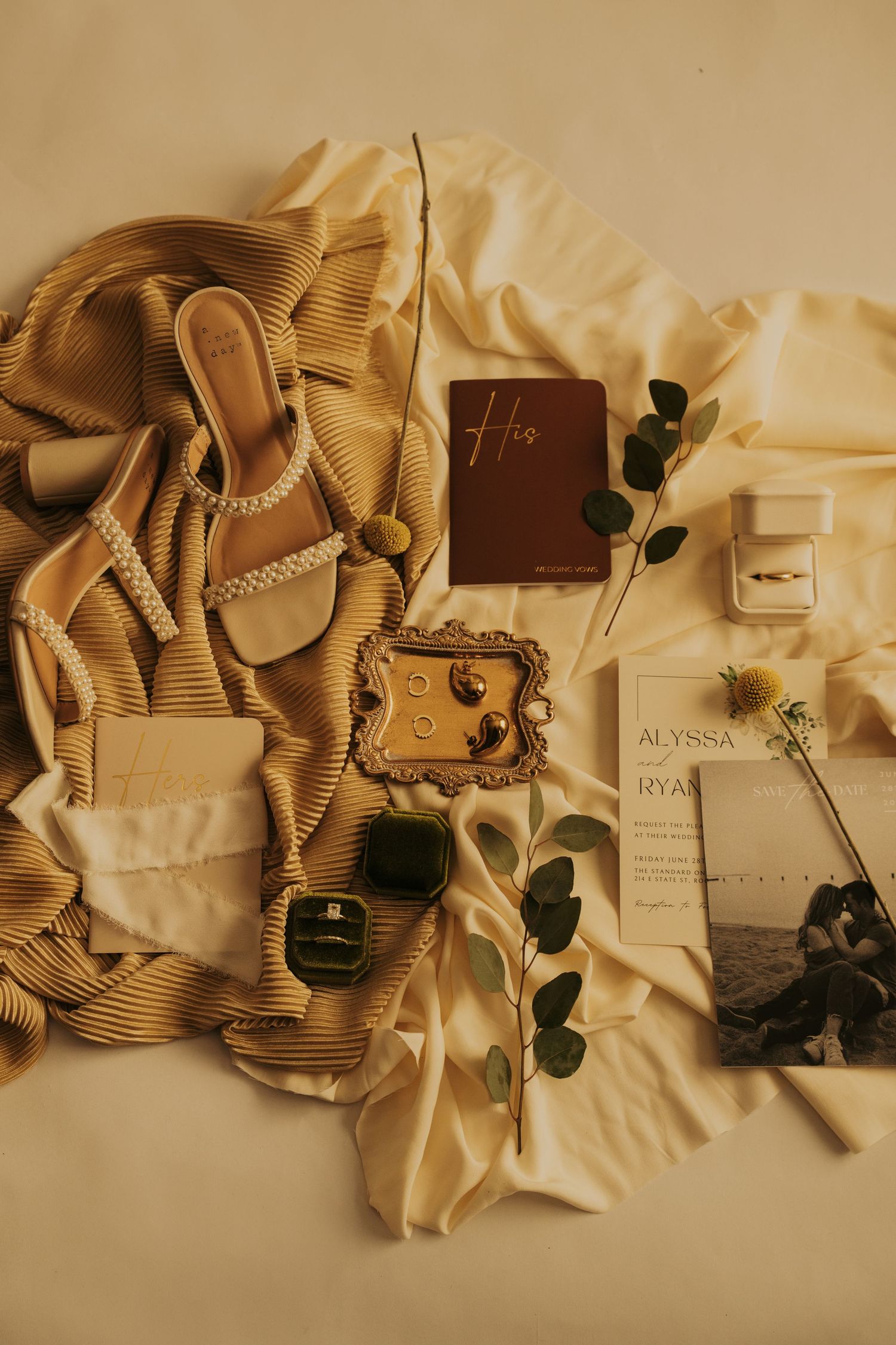 A series of vintage-style beige and brown wedding invitation cards arranged with eucalyptus leaves on a cream background.