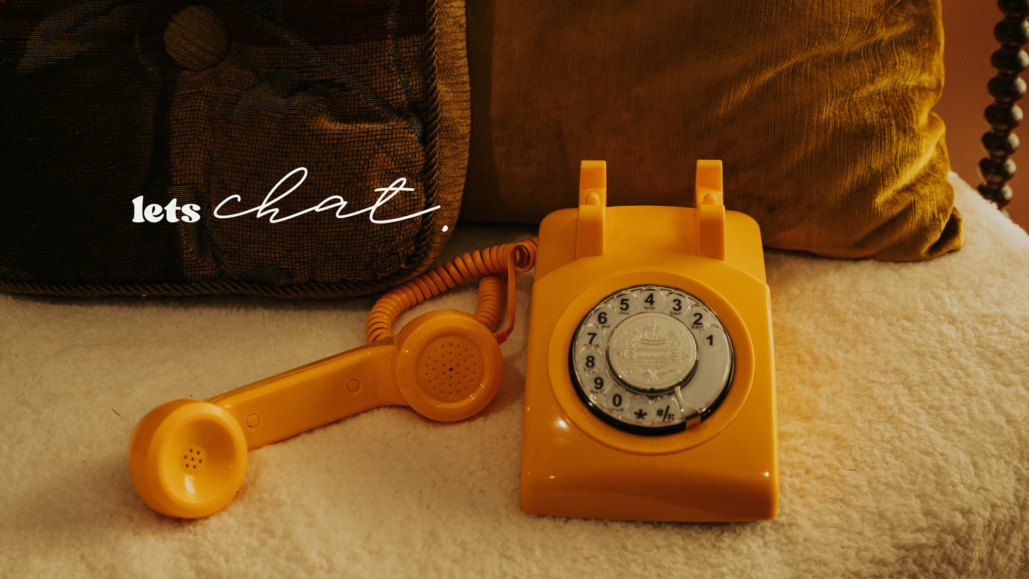 A collection of vintage orange rotary telephones arranged in a row against a white background.