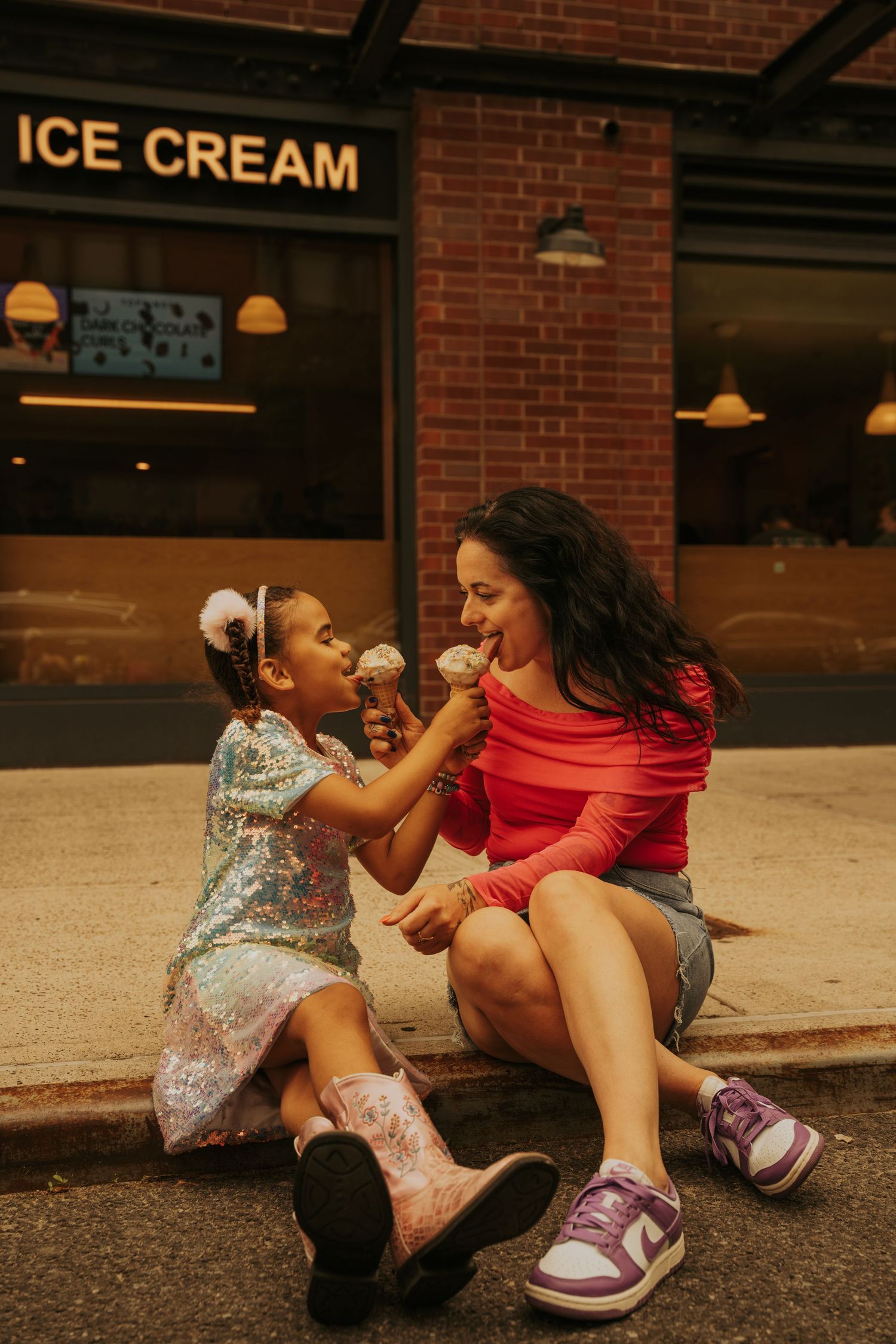 A heartwarming scene of sharing ice cream outside a brick storefront with vintage lighting fixtures.