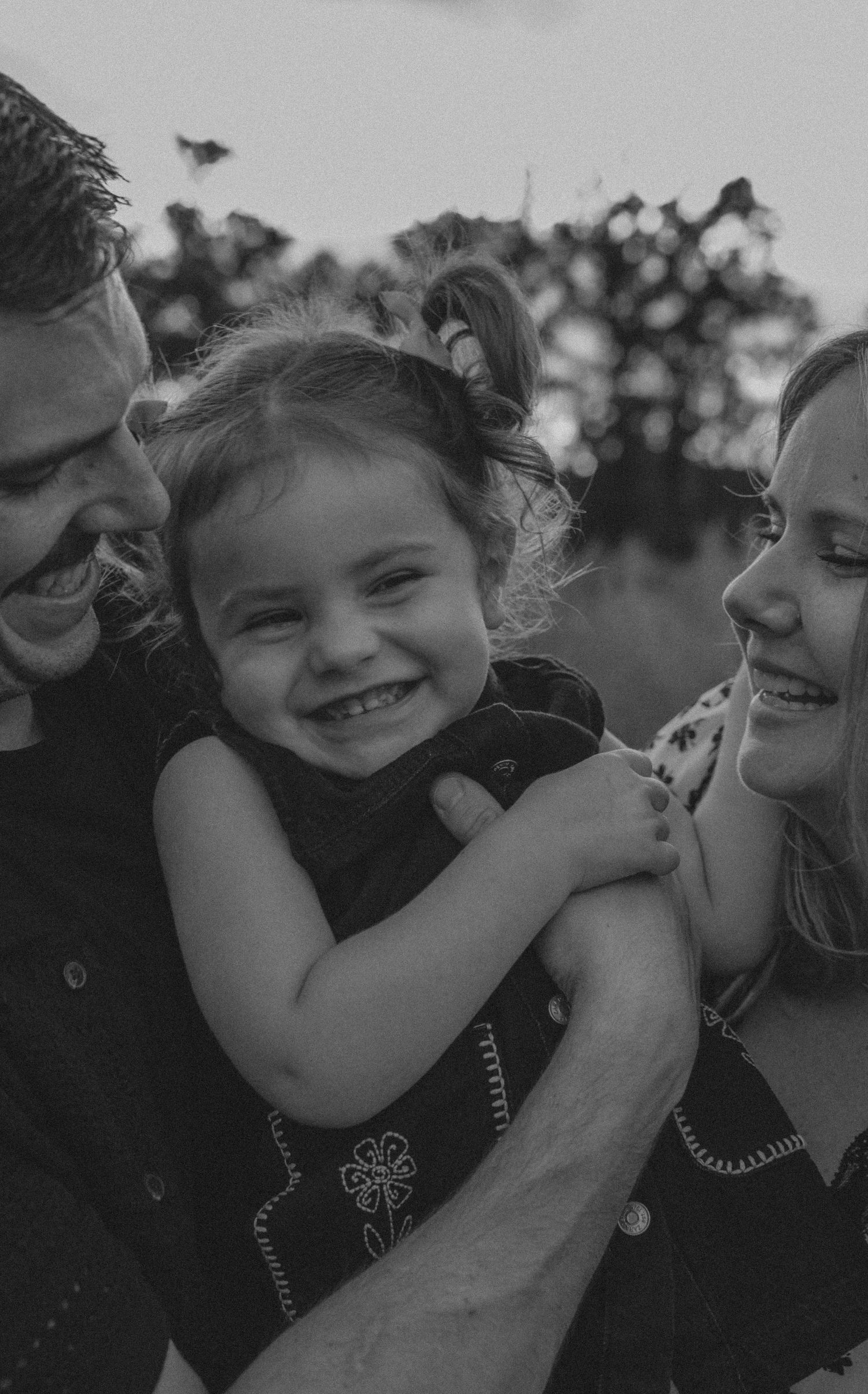 Black and white photo showing close-up candid moments of laughter and embraces between people in dark clothing.