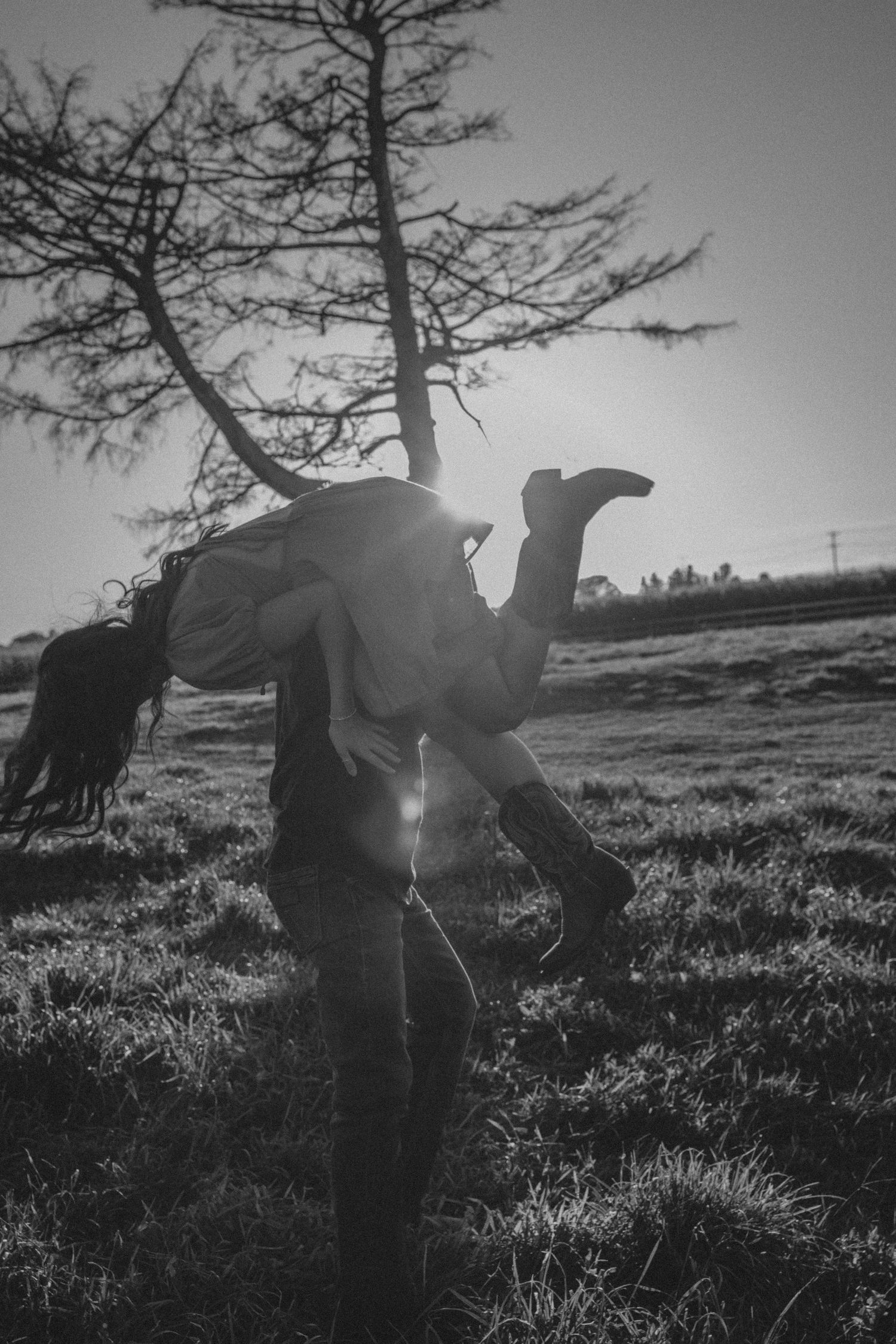 A series of black and white photos showing silhouettes of figures bending down in a grassy field at sunset.