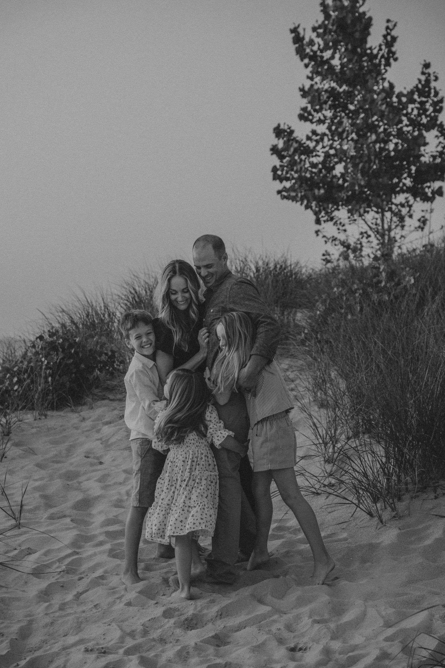 A vintage black and white sequence of photos showing a playful moment on sand dunes with beach grass in the background.