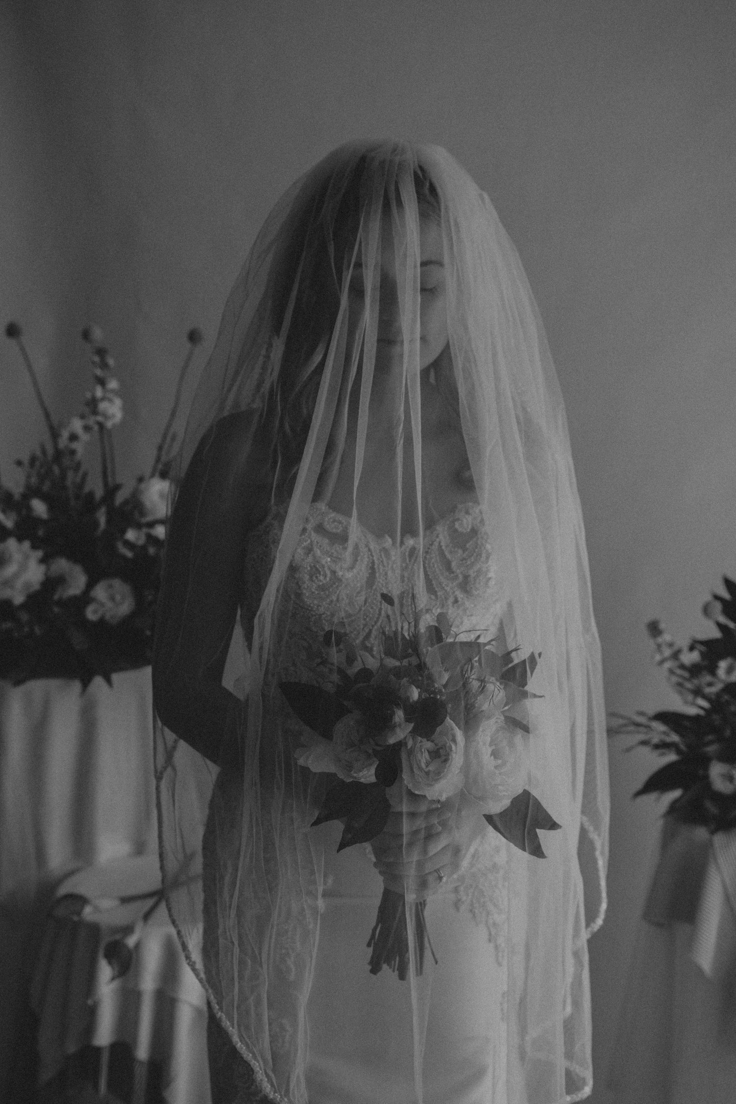 A black and white photo series showing a bride wearing a delicate lace veil in different ethereal poses.