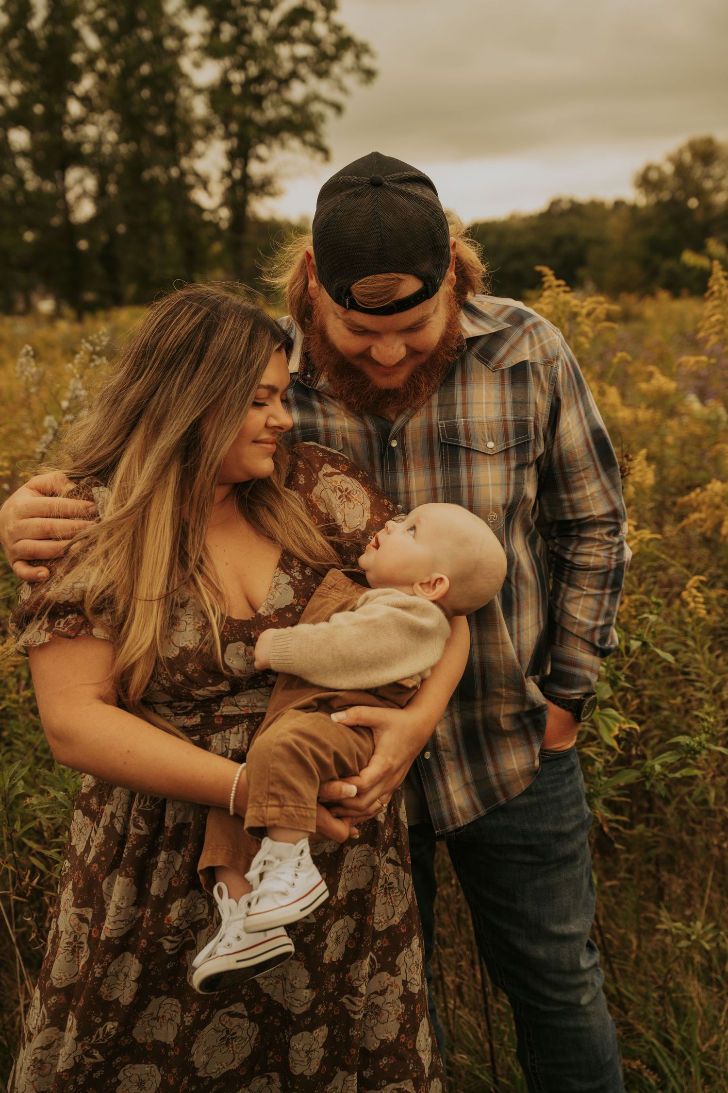A family shares tender moments together in a golden wildflower field during sunset.