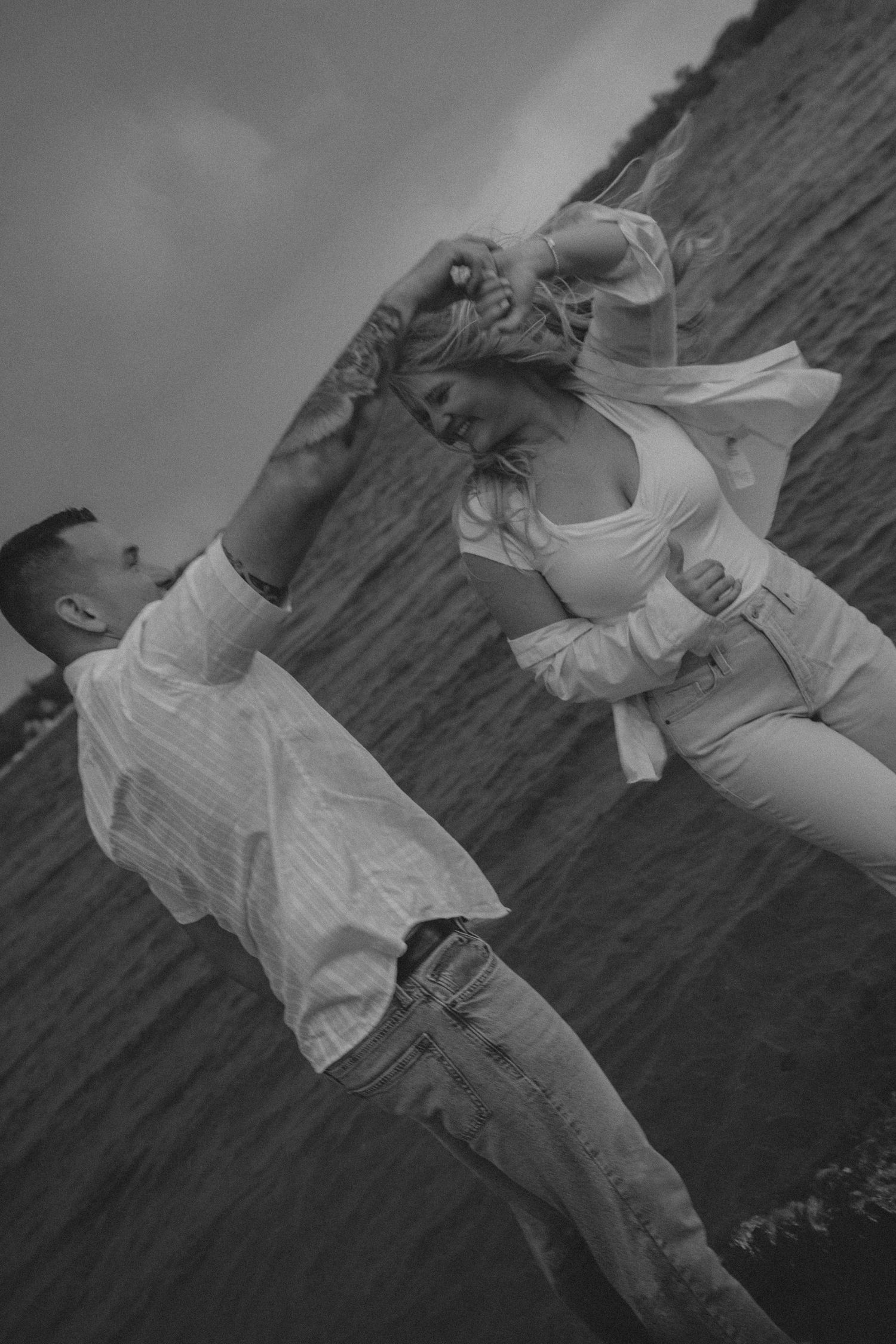 A black and white photo series shows a person in white clothing dancing expressively on a dark surface.