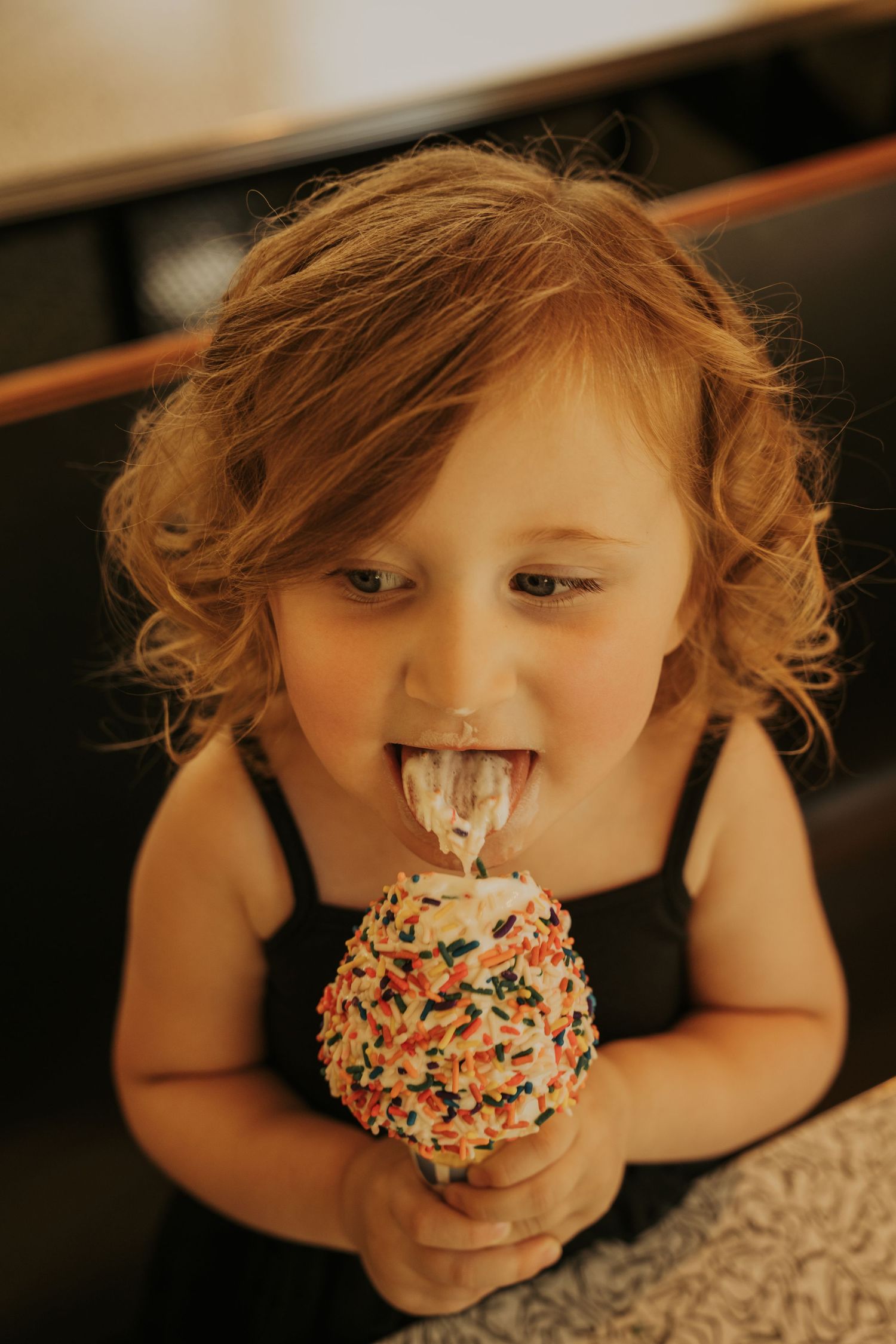 A child playfully eats a frosted donut covered in colorful sprinkles in a series of close-up photos.