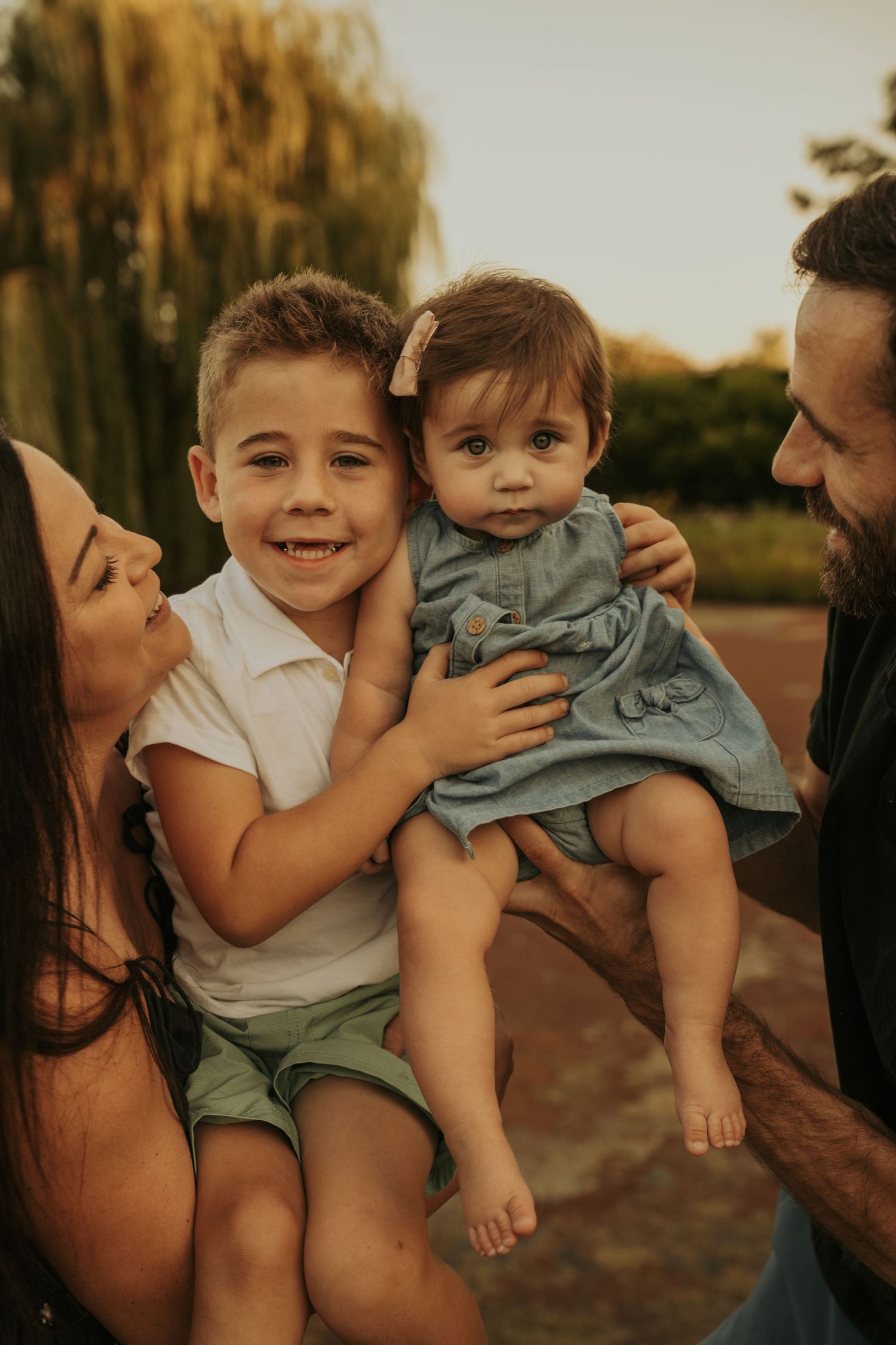 A heartwarming family moment captured in warm sunset lighting as parents share joyful interactions with their child.