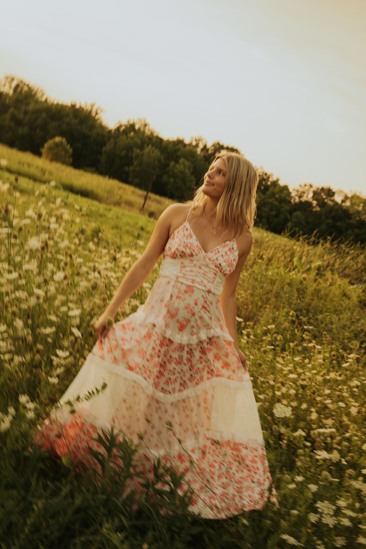 A person in a floral white dress twirls gracefully through a blooming daisy field at golden hour.