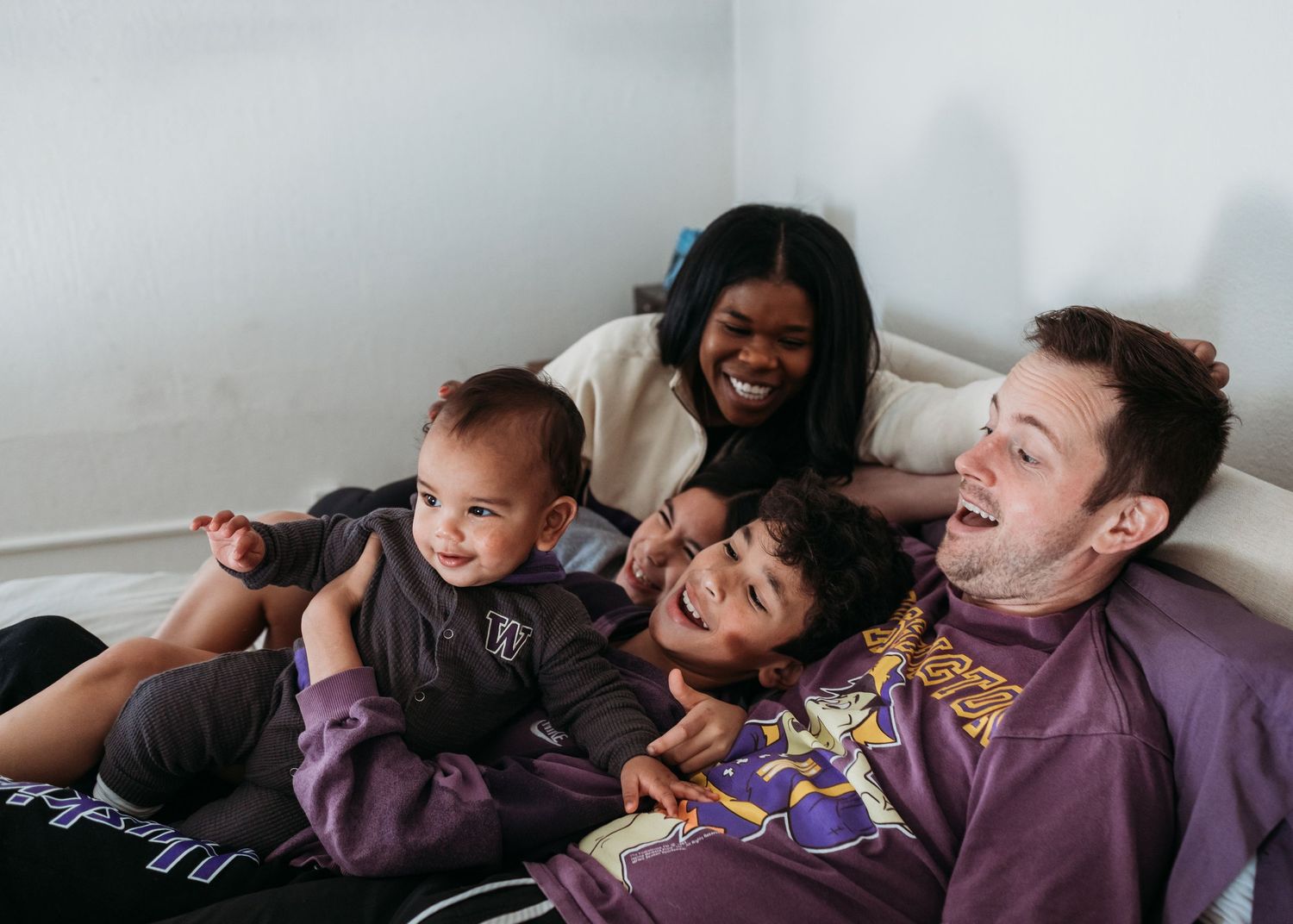 A happy group lounges together on a couch while playing and laughing during a relaxed moment at home.