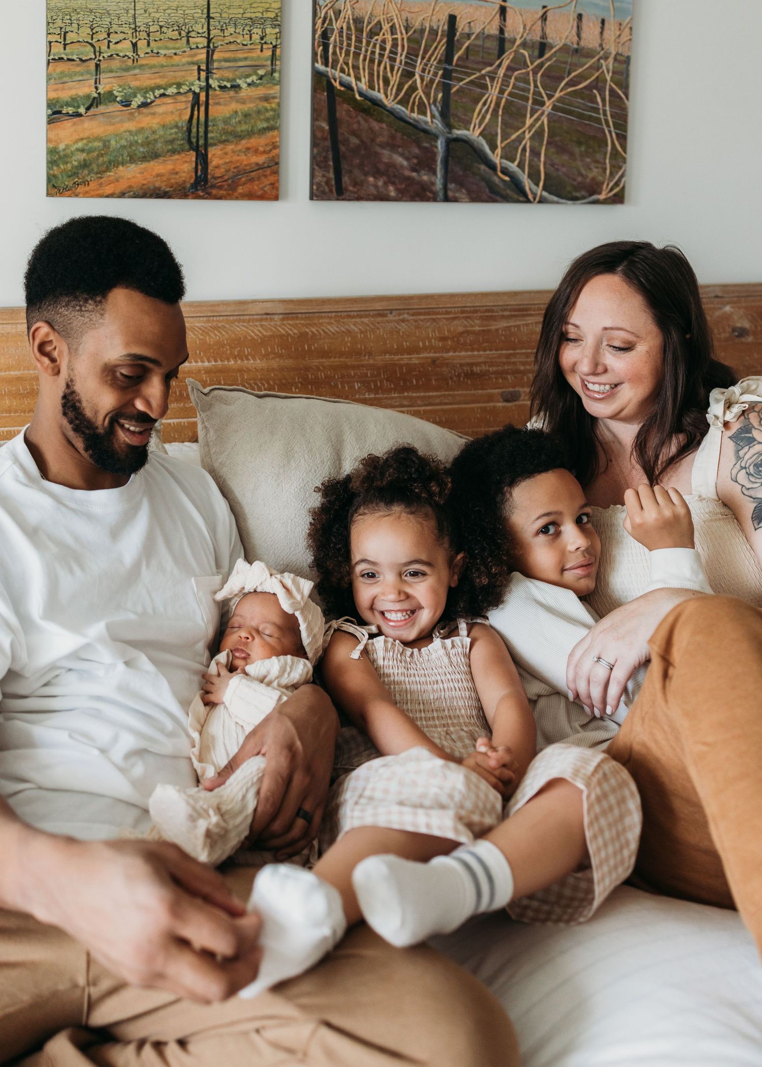 Family relaxes together on couch at home with artwork on wall behind them.