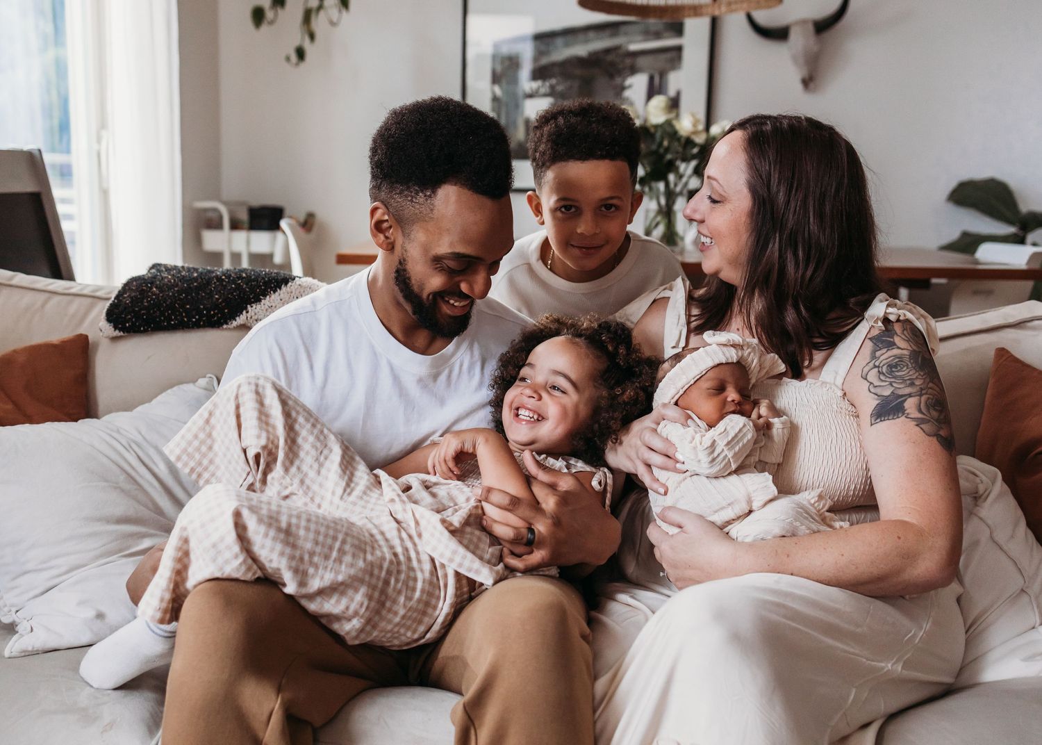 A family relaxes together on a cozy white bed, sharing intimate moments and cuddles.