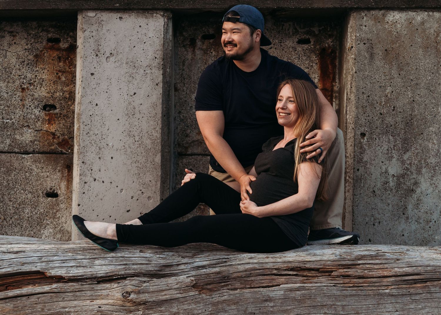 A couple sits together on rustic wooden steps in a romantic engagement photo session.