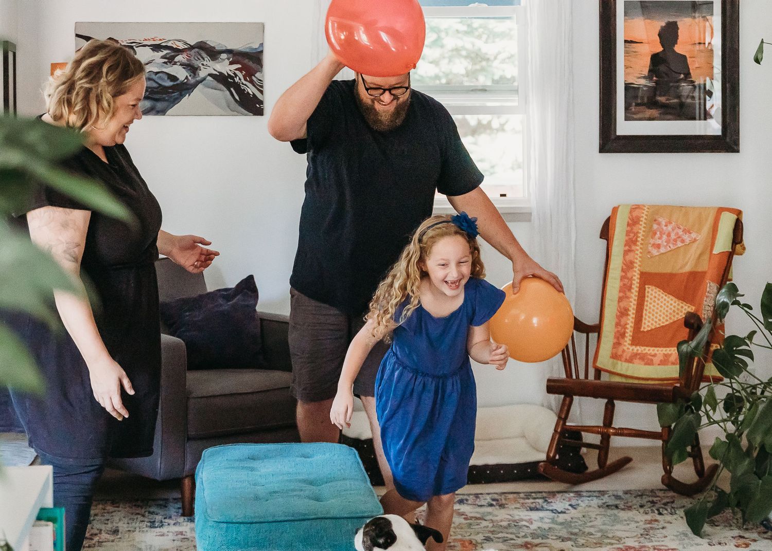 A joyful scene in a living room with balloons and decorations during a celebration.
