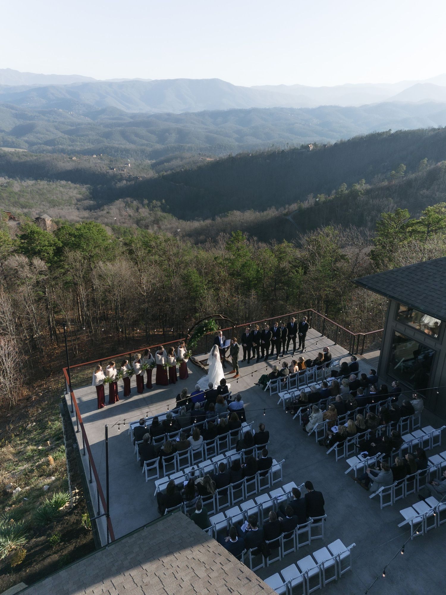 A scenic mountain wedding ceremony setup with white chairs and a rustic wooden arch overlooking the Blue Ridge Mountains.