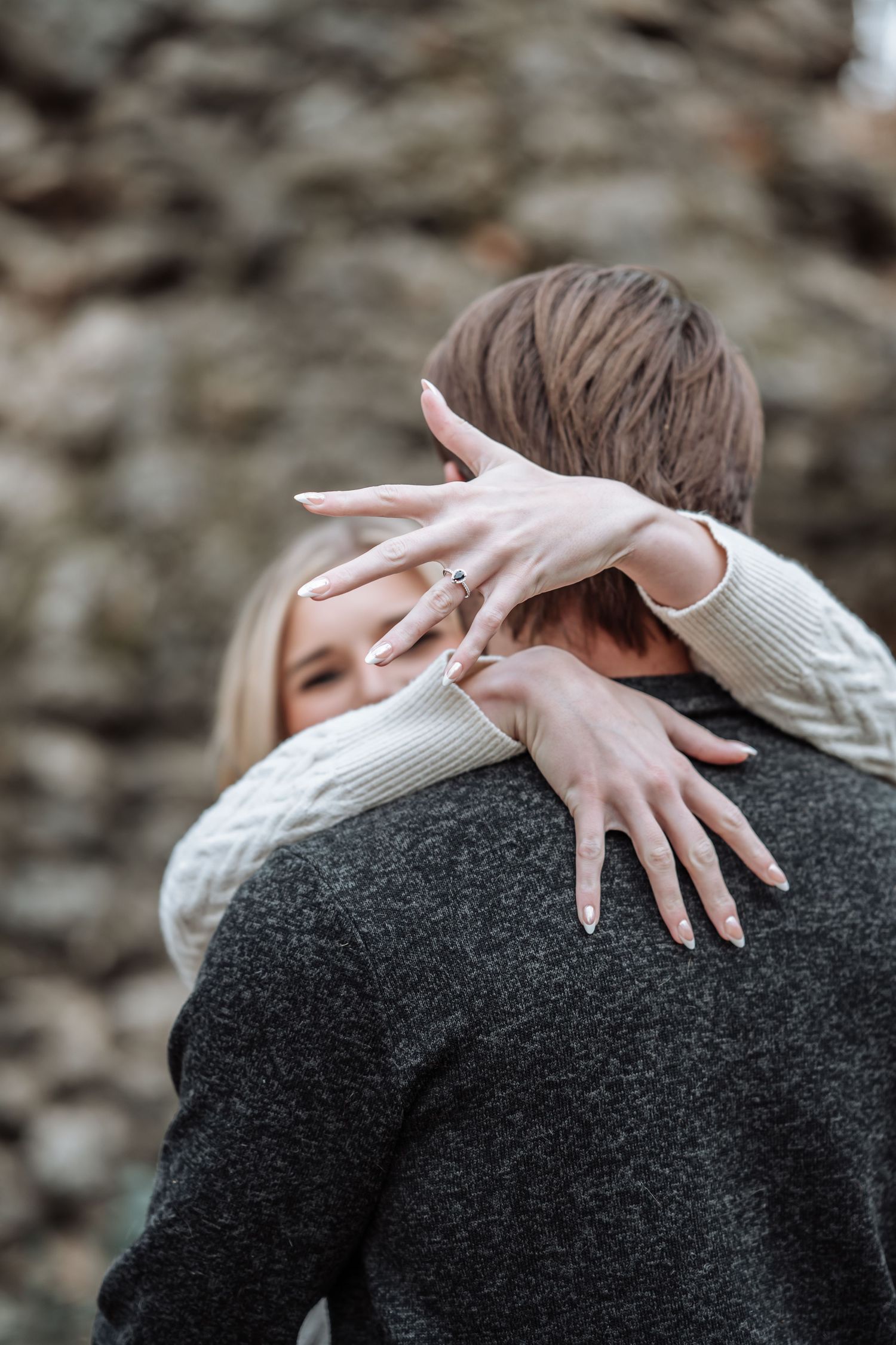 A pale hand with manicured nails rests dramatically on a dark sweater-clad shoulder in an artistic portrait series.