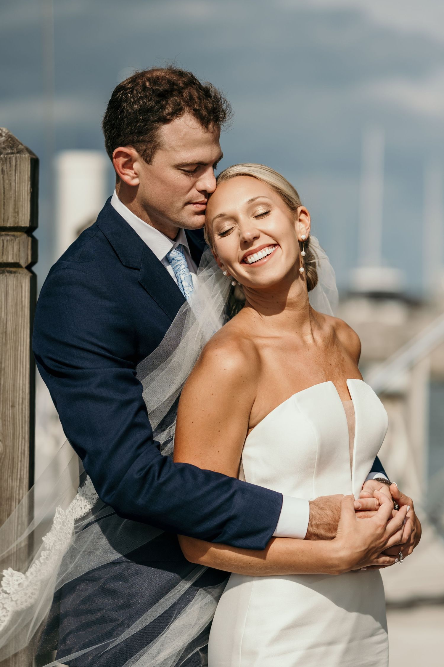 Romantic wedding couple embracing in a series of intimate poses by the water.