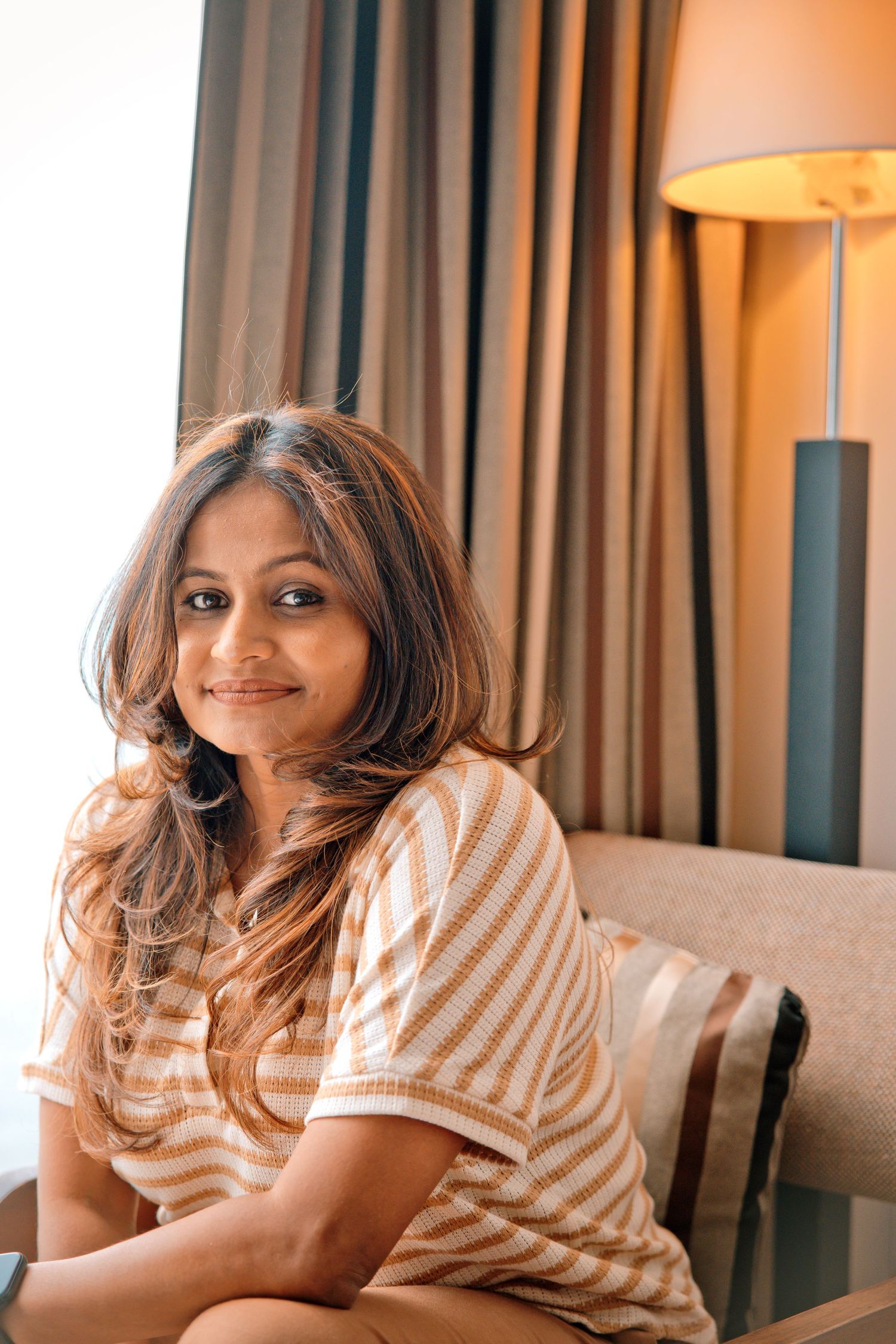 Professional headshot of a woman smiling confidently, in a casual yet polished striped top, suitable for team pages or 'about us' sections.
